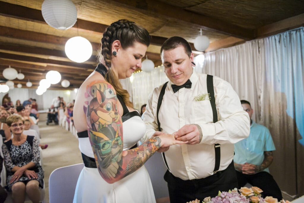 tattooed couple is changing rings at their wedding ceremony