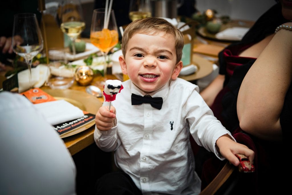 a little boy is holding a Halloween lollipop in his hand and grimaces