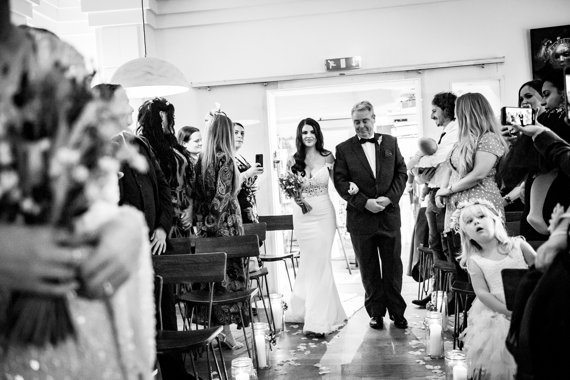 Bride walking down the aisle with her father, surrounded by family and guests at The Square Club Bristol.