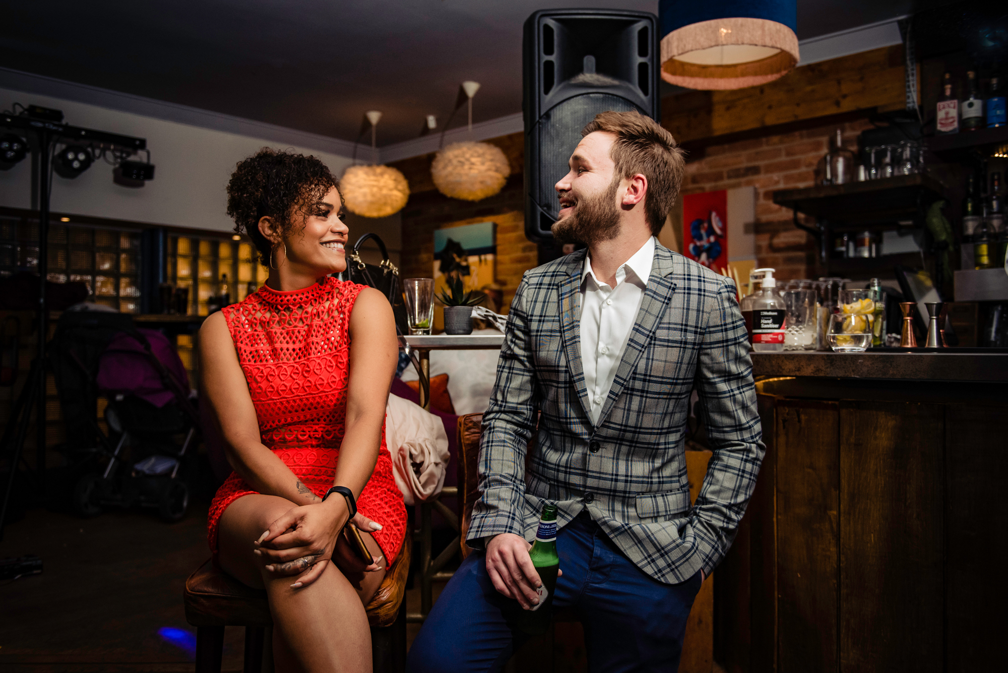 Two guests chatting and laughing at the bar during an evening wedding reception at The Square Club Bristol.