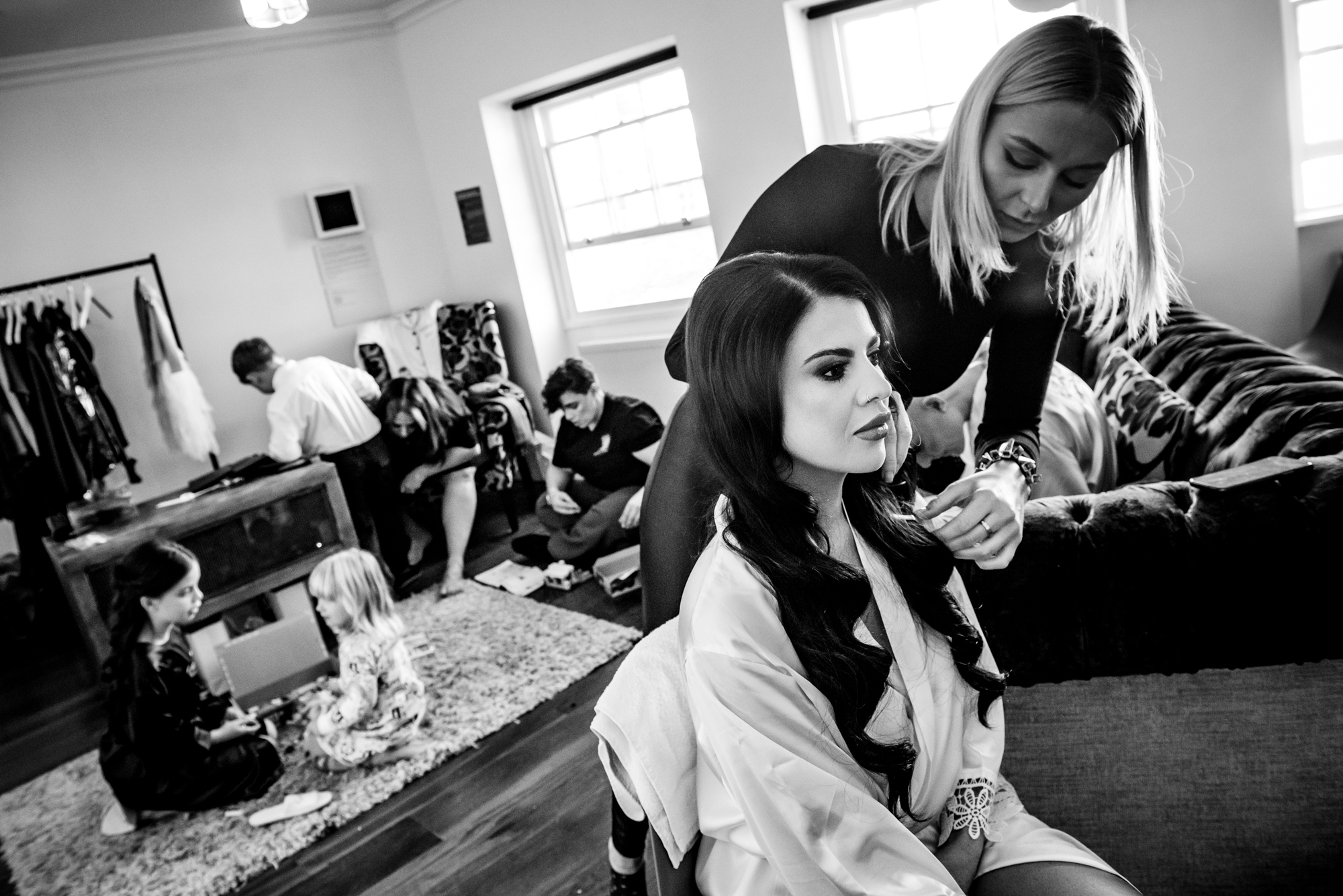 One bride gets her makeup done while family and kids fill the room with laughter.