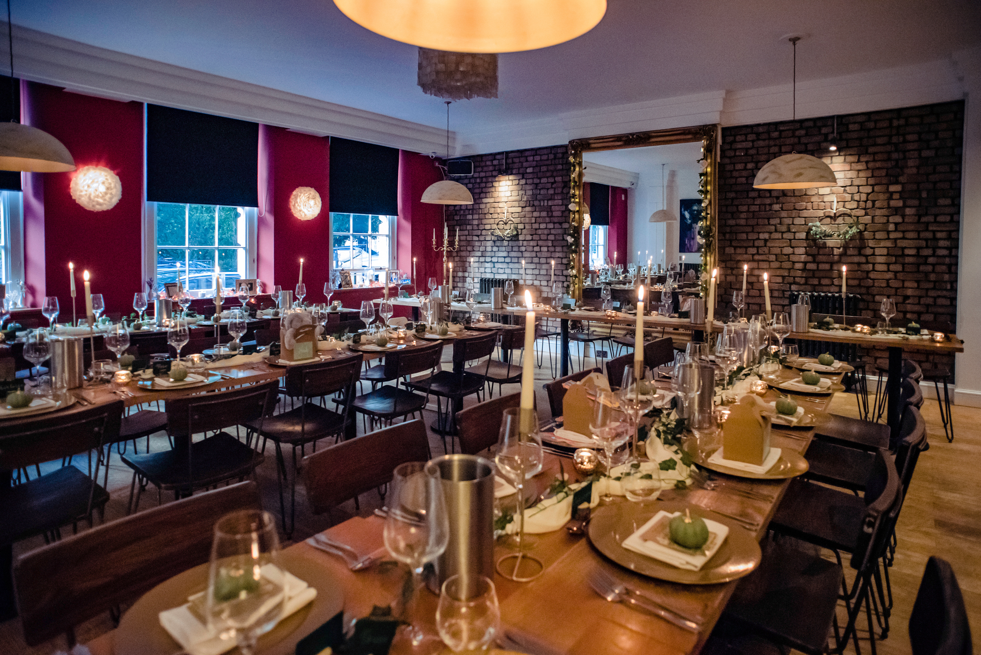 Warm, candlelit wedding reception setup with gold plates and brick walls inside The Square Club Bristol.