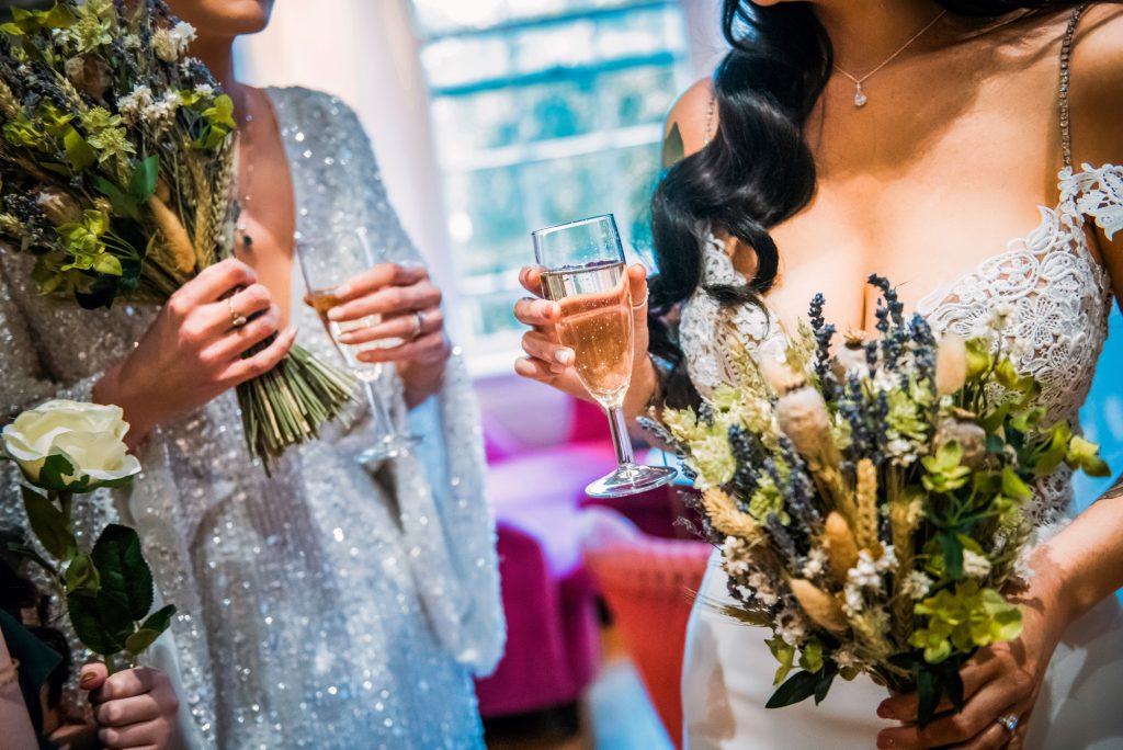 Brides holding champagne and dried flower bouquets before the celebration at The Square Club Bristol.