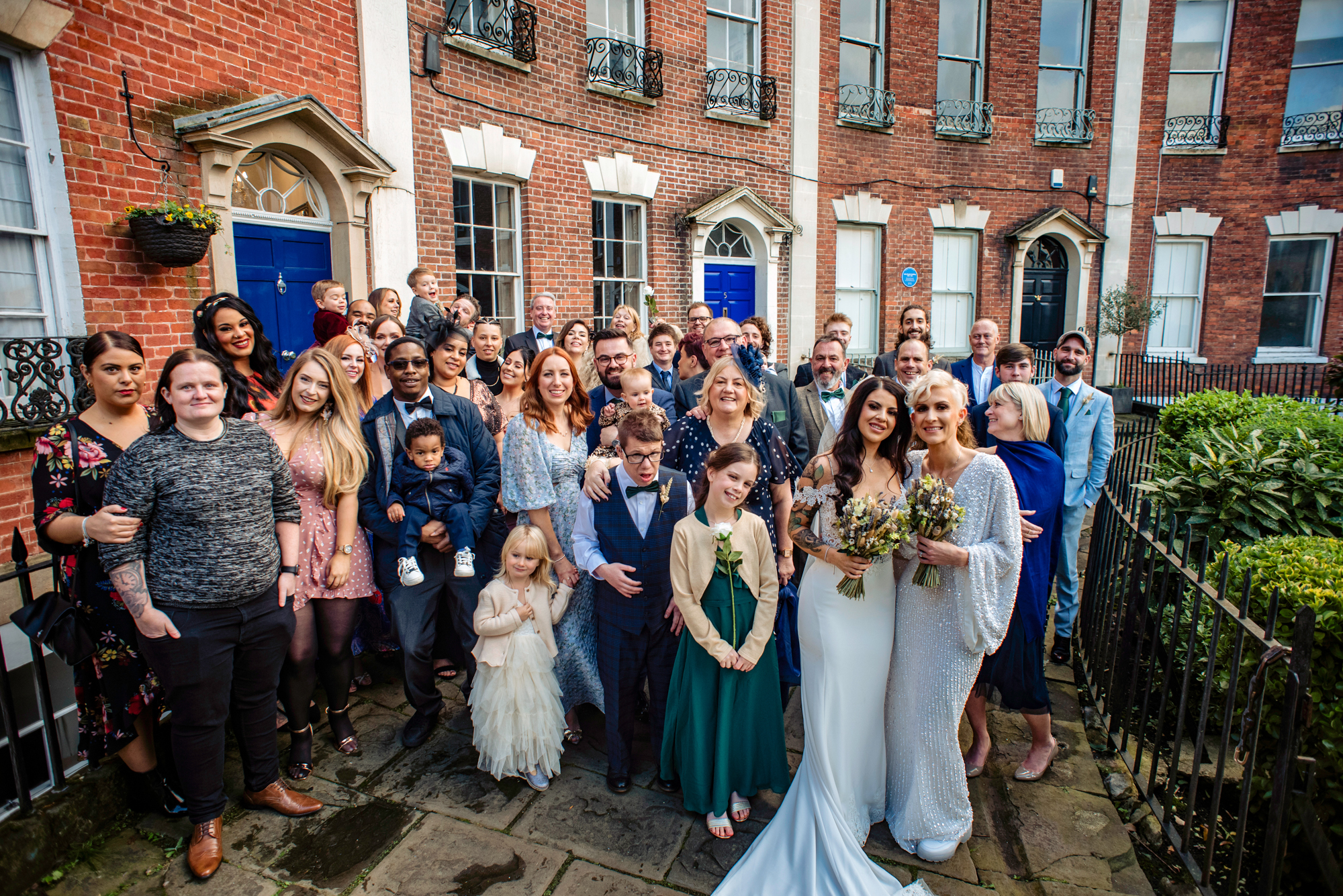 Group wedding portrait of family and friends with the brides outside of Berkeley Suites.