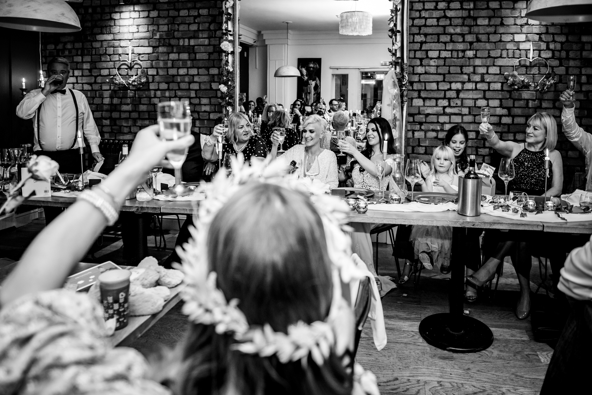 Guests raising their glasses during a joyful wedding toast.