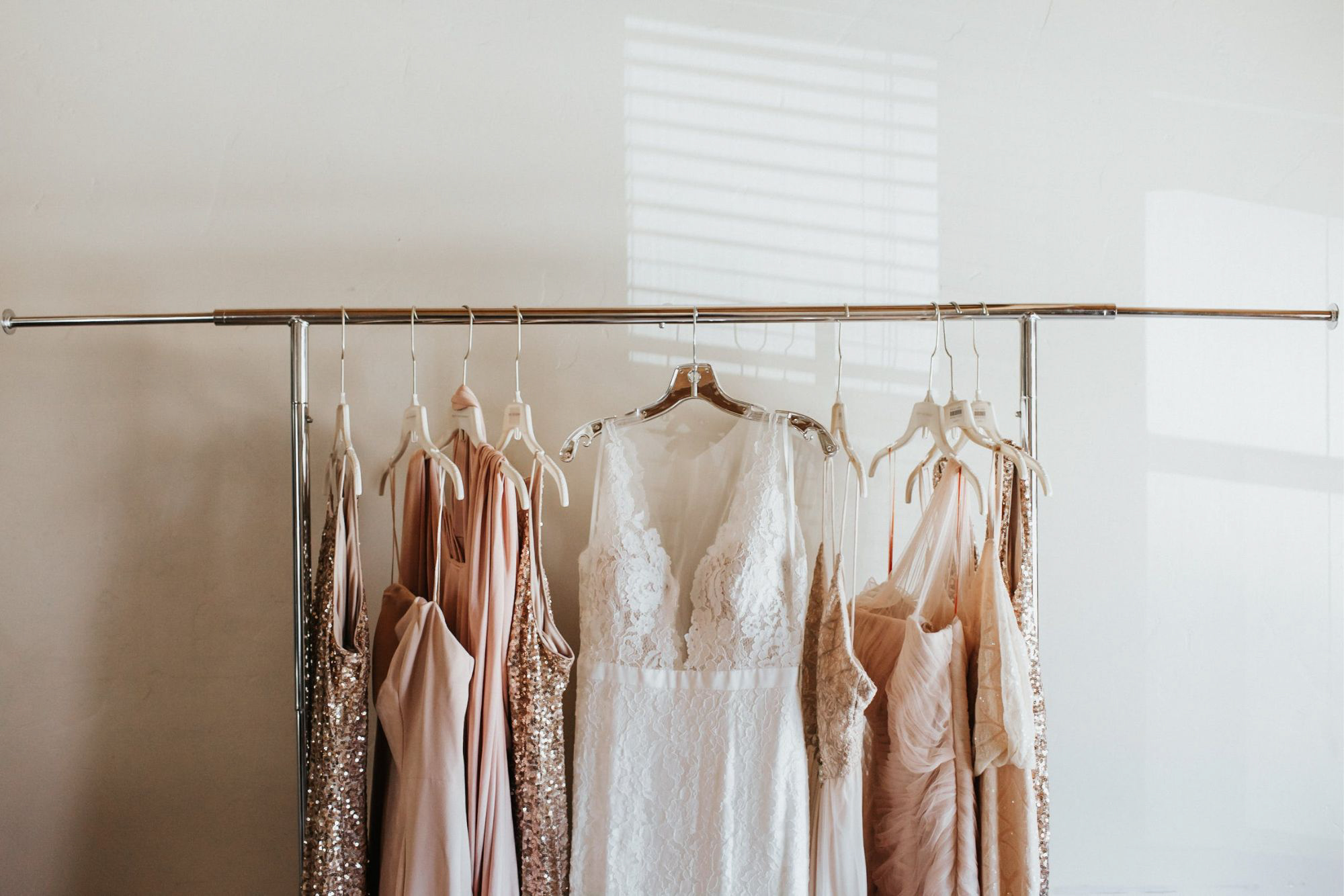Wedding dress and bridesmaid dresses hanging on rack in bridal studio.