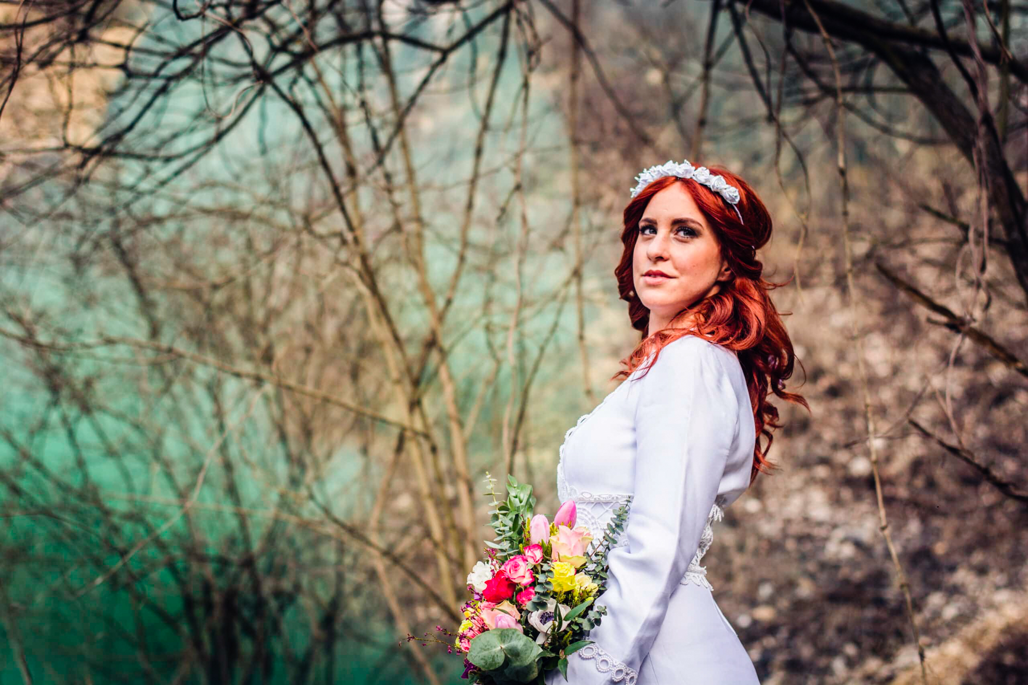 Red-haired bride looks over her shoulder with bouquet in hand and green smoke behind.