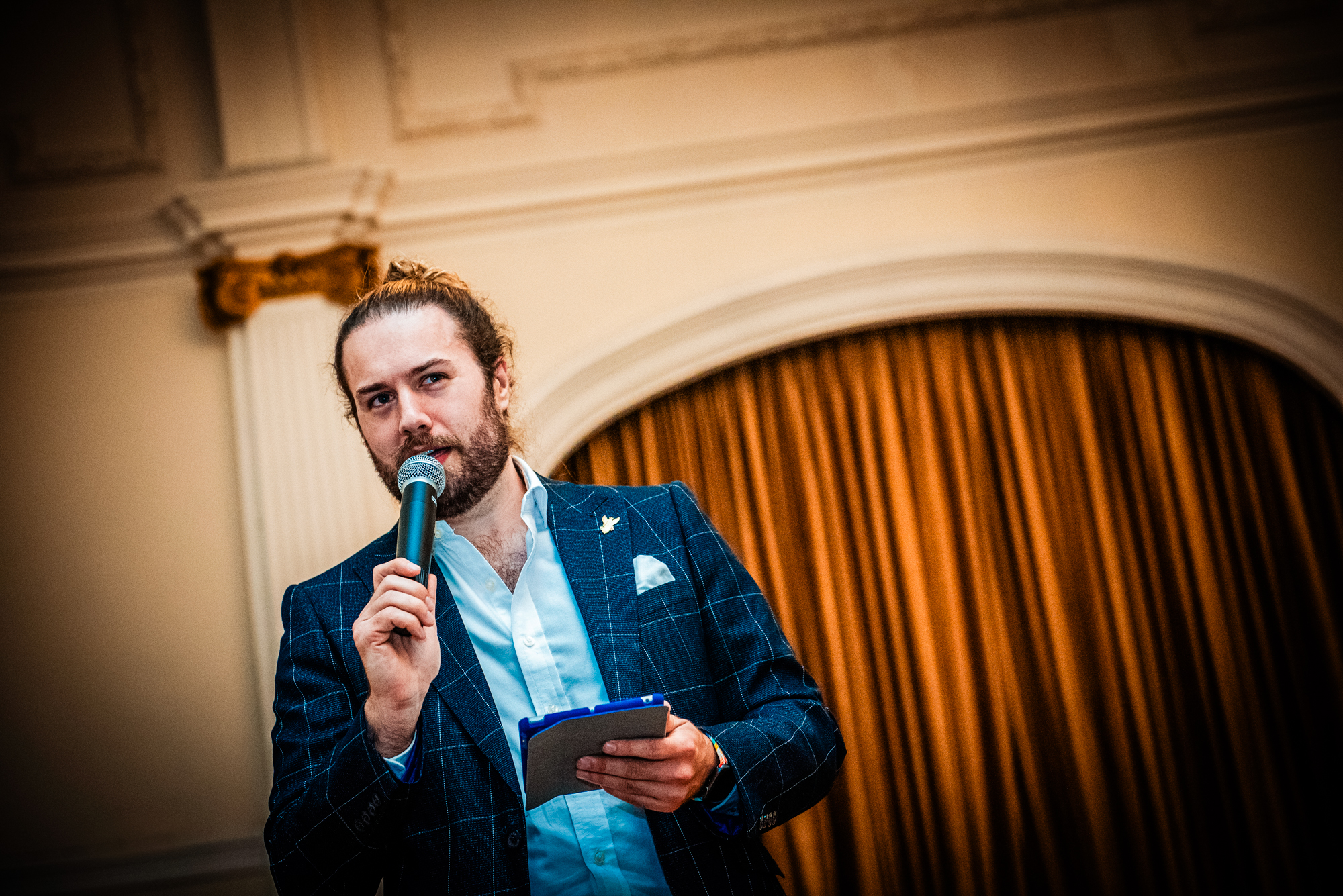 Speaker holding a microphone during the Galenicals Awards ceremony at Bristol Grand Hotel.