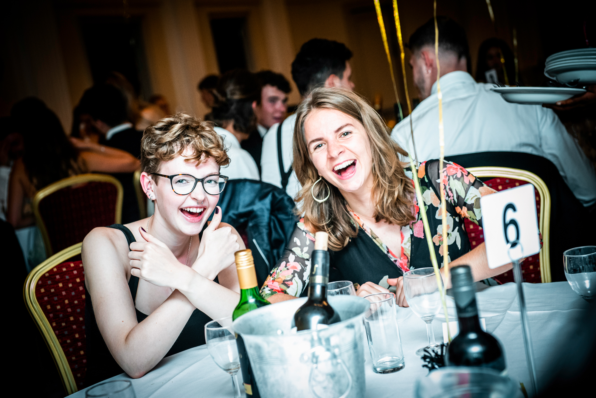 Two guests laughing and posing beside table six during the Galenicals Awards celebration.