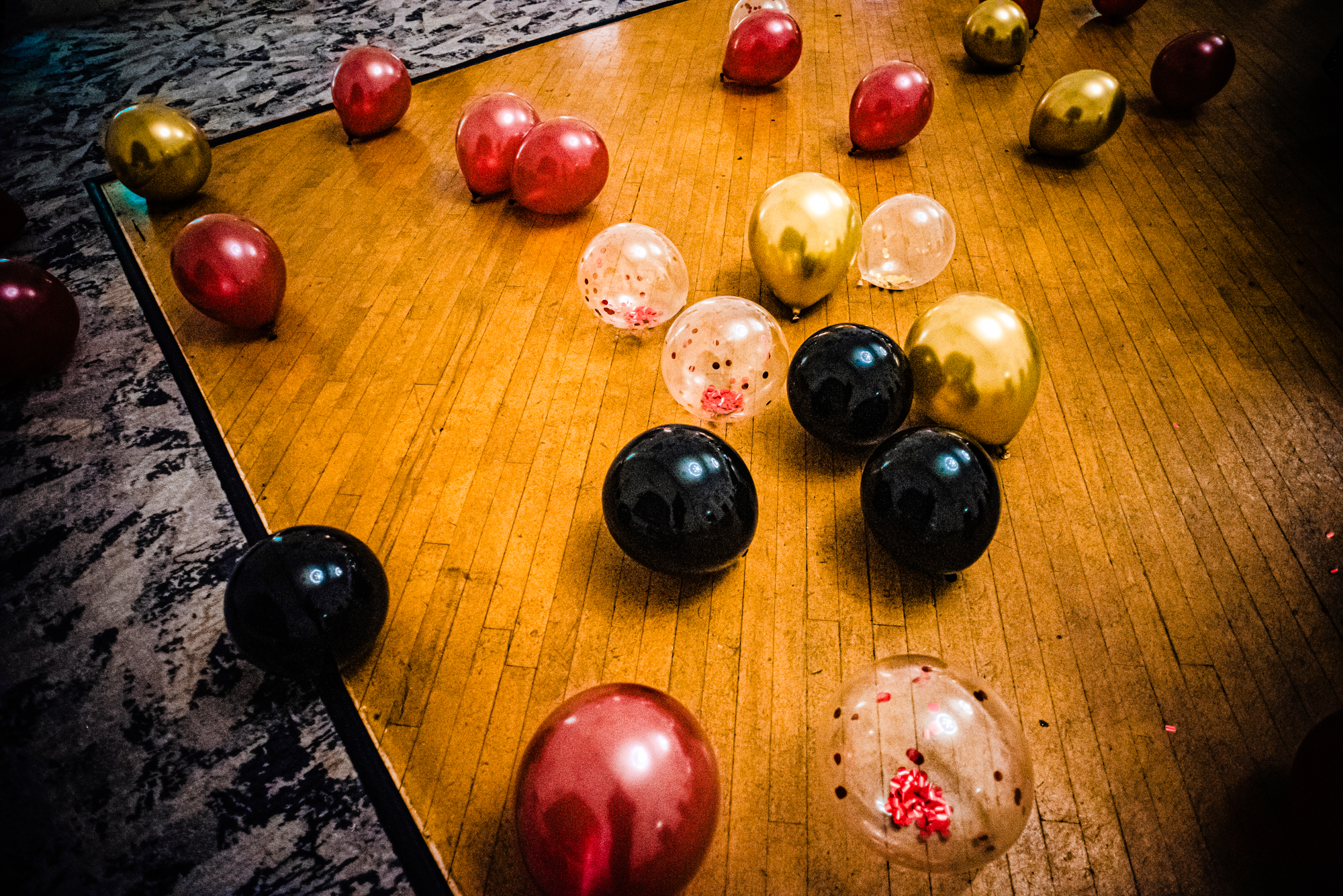 Black, gold, red, and clear balloons scattered across the dance floor before the Bristol awards event.