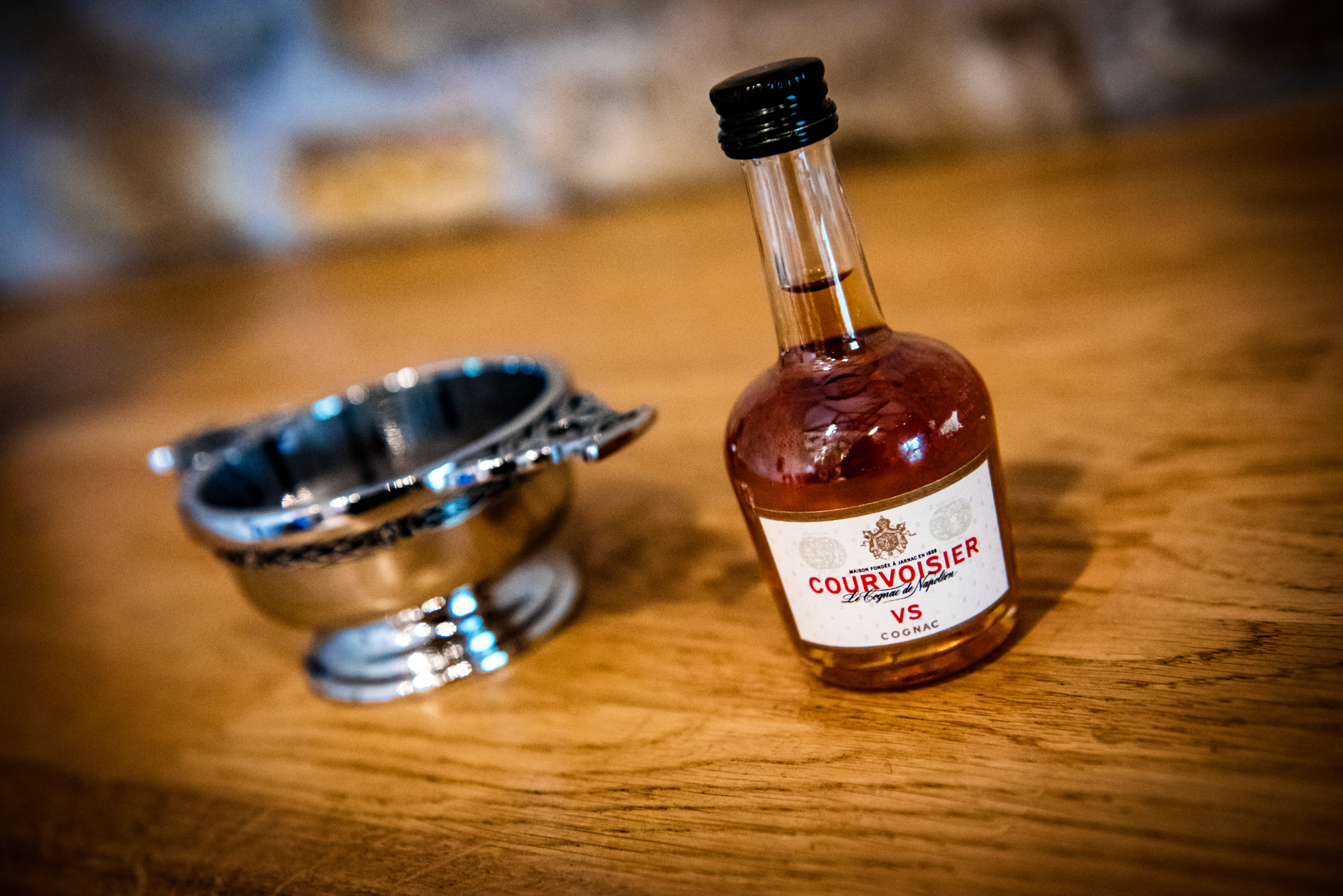 A mini Courvoisier bottle sits beside a silver cup, ready for a traditional wedding toast.