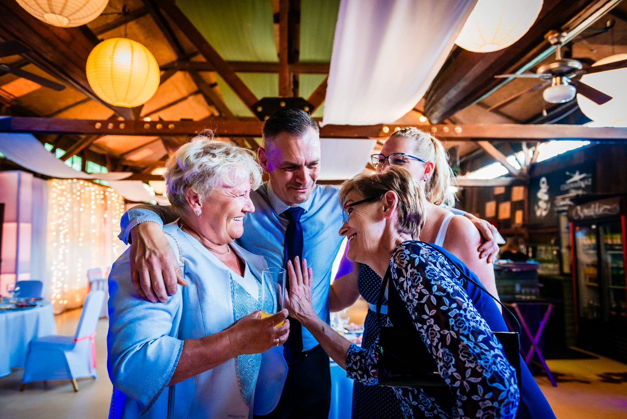 Family members hugging and laughing during emotional moment at alternative Budapest wedding reception.