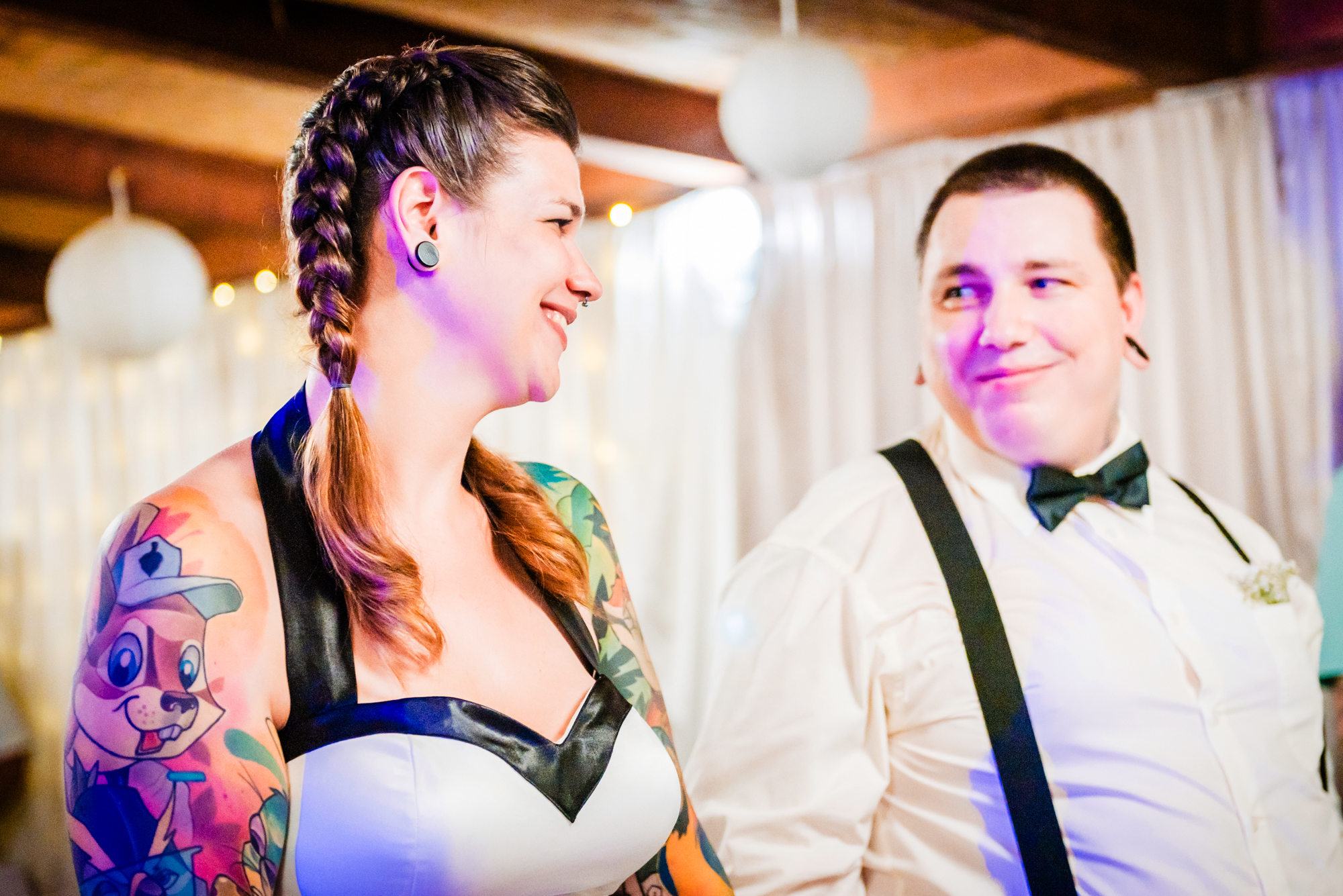 Alternative bride with colourful tattoos smiling at groom during intimate wedding ceremony in Budapest.