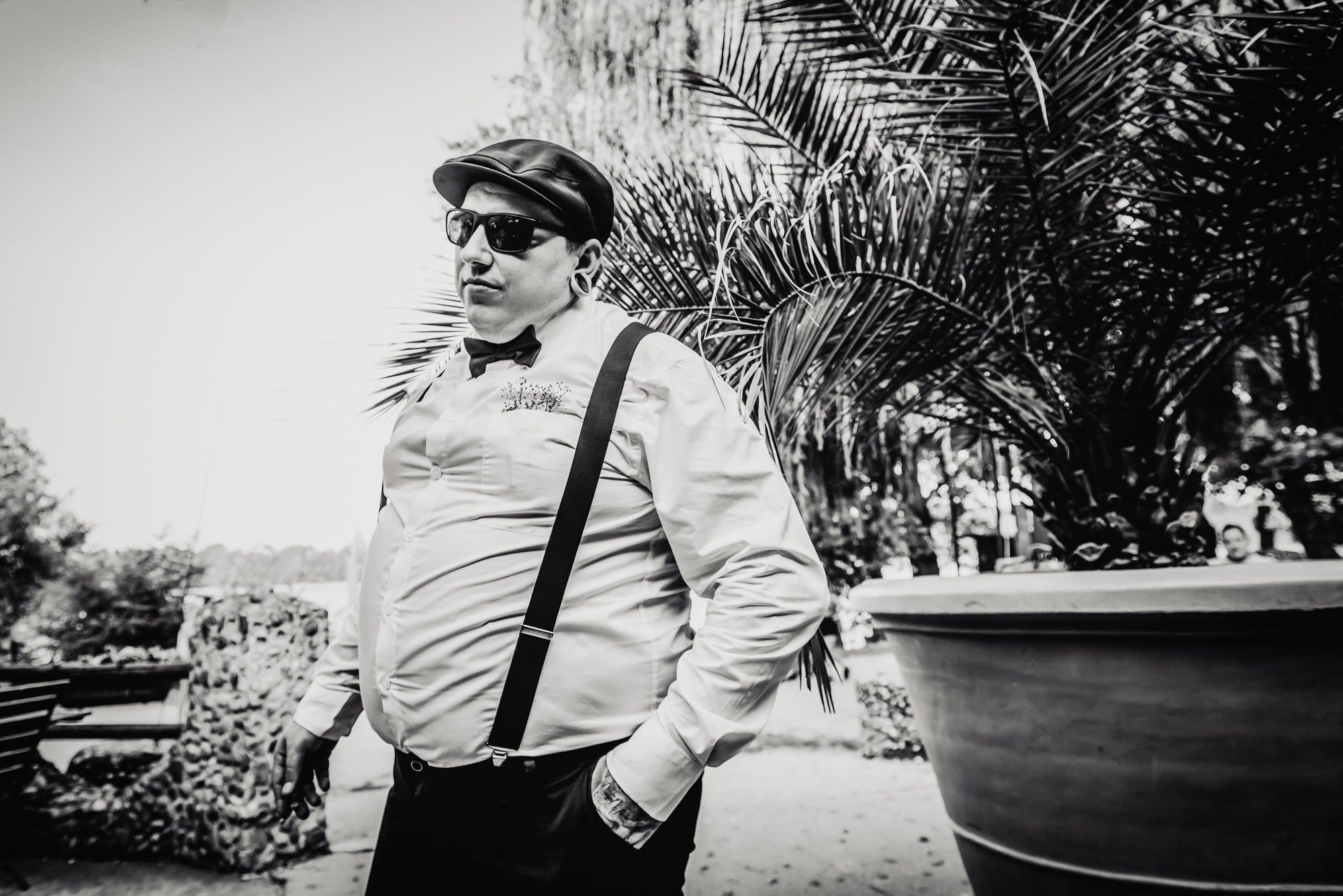 Alternative groom wearing sunglasses and suspenders during relaxed outdoor wedding portrait in Budapest.
