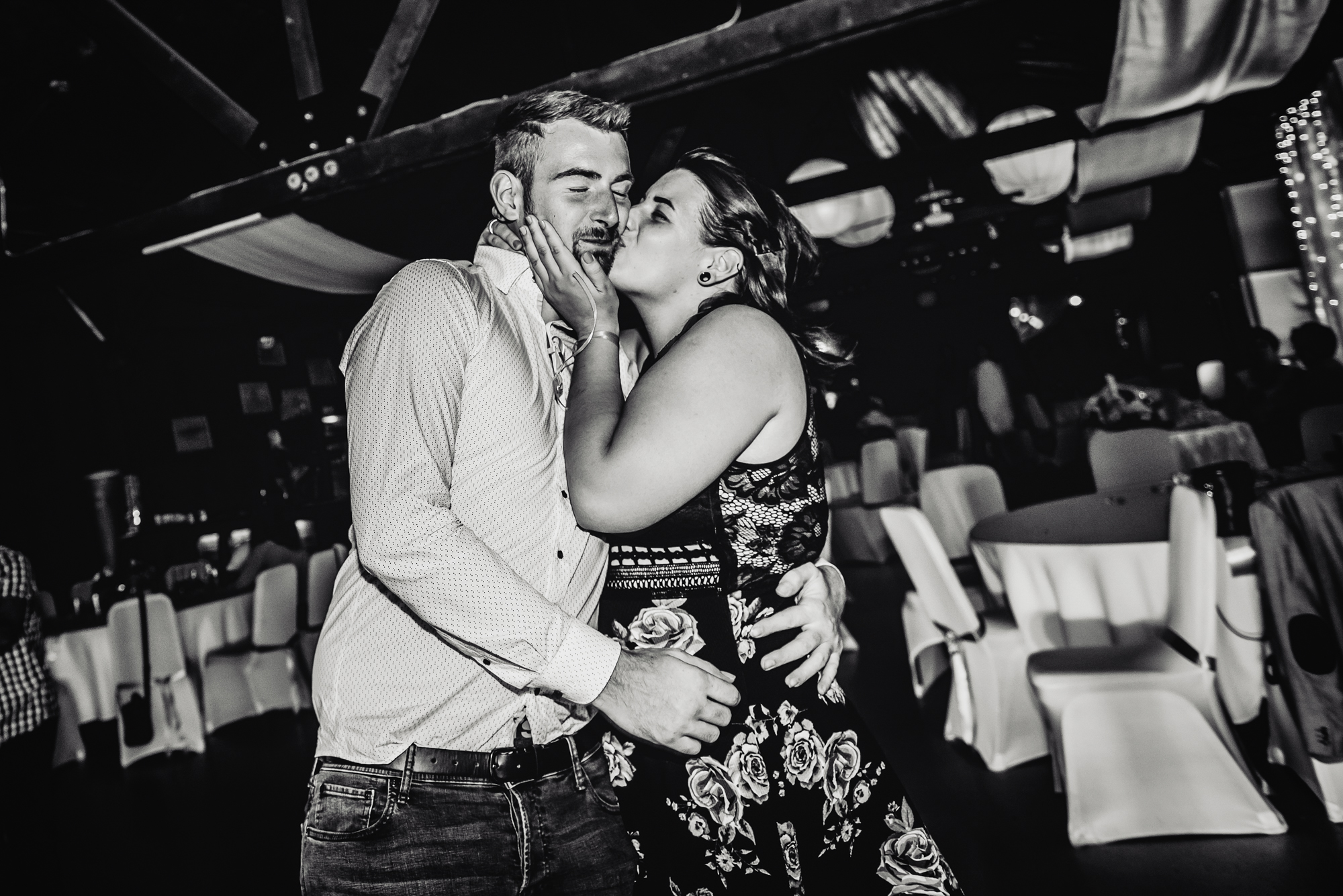 Wedding guest kissing partner on the cheek while dancing at intimate Budapest wedding reception.