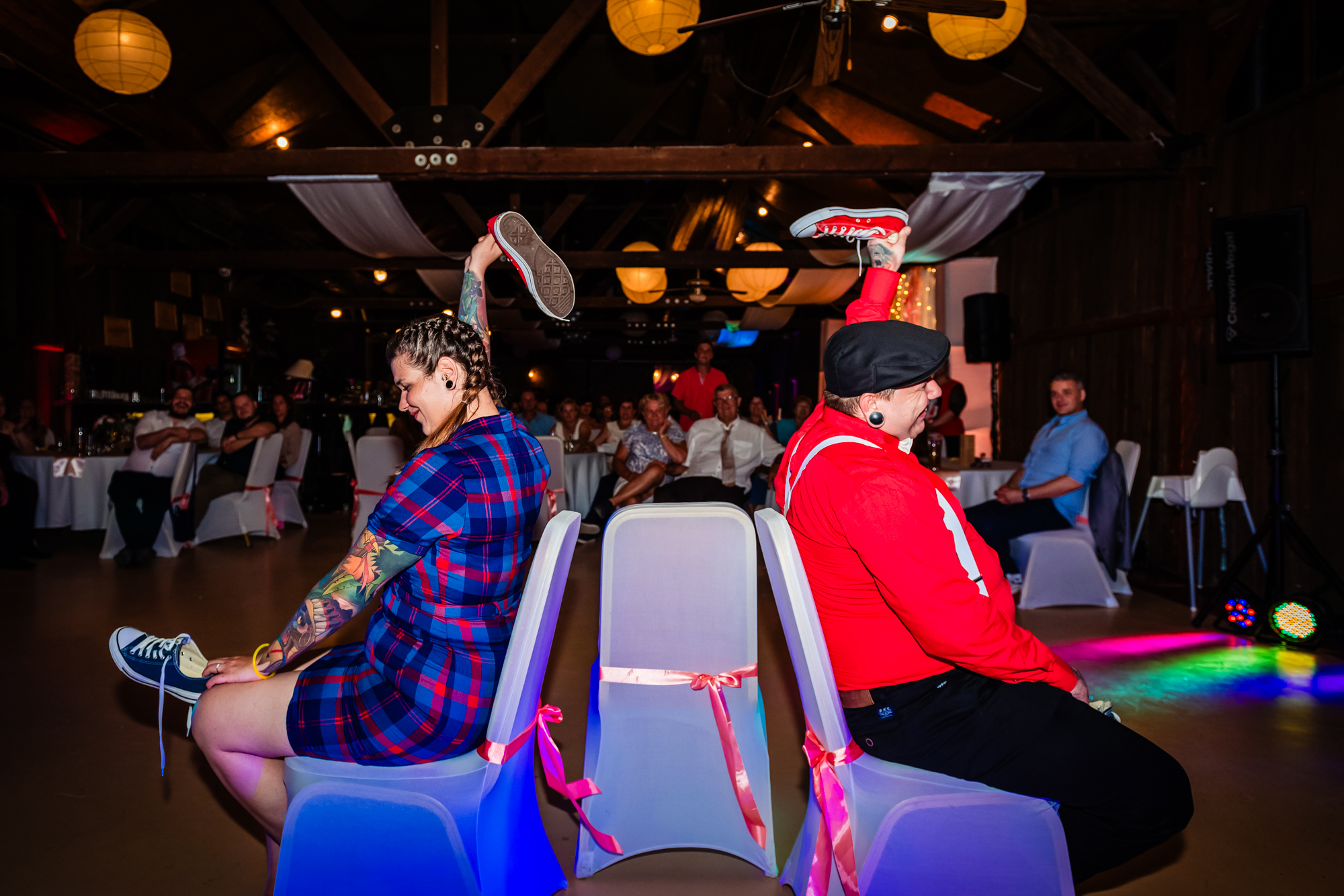 Alternative bride and groom holding trainers during fun wedding shoe game at Budapest reception venue.