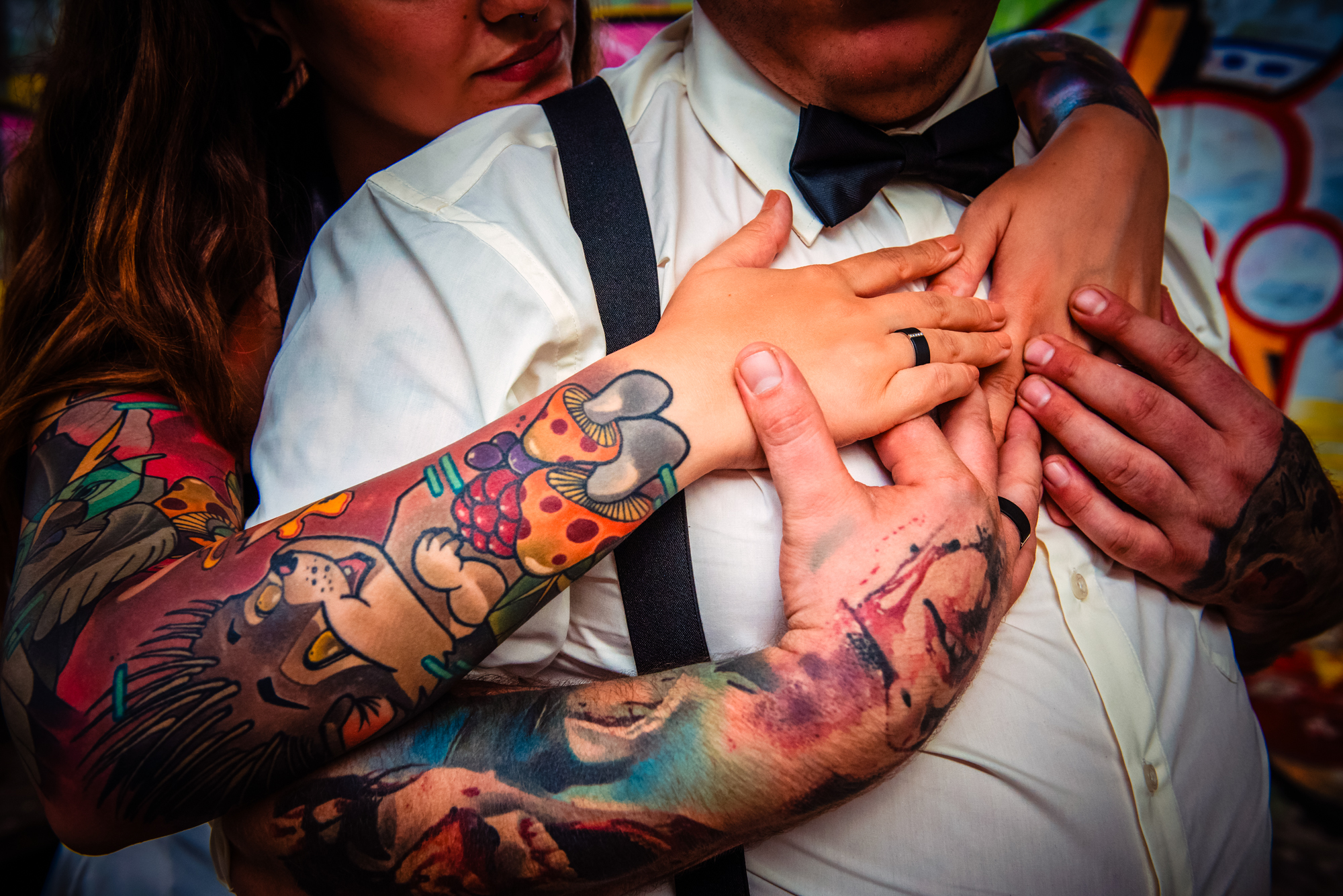 Close-up of tattooed newlyweds holding hands and wedding rings during alternative Budapest wedding portraits.