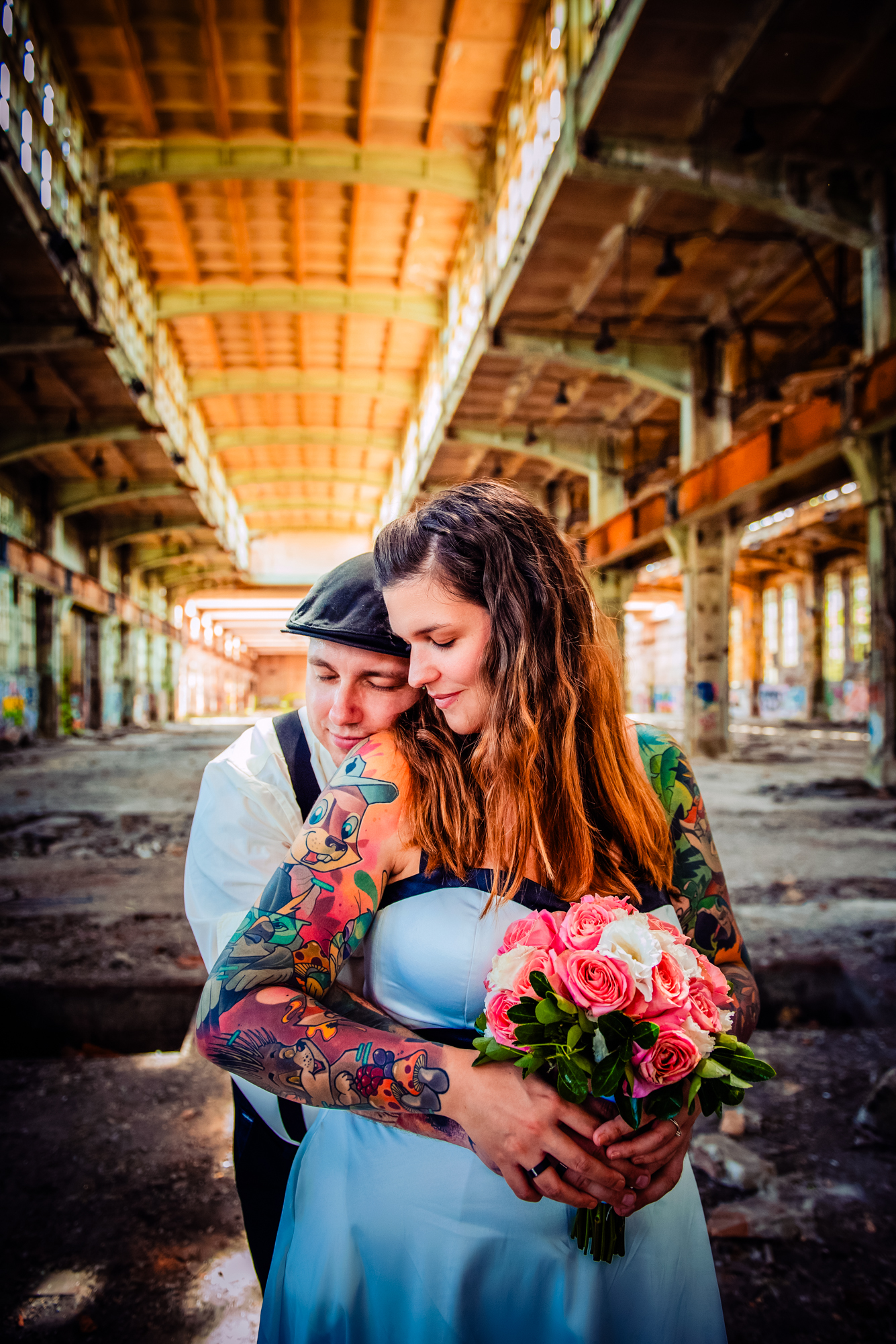 Alternative wedding couple holding pink roses inside a graffiti-covered abandoned factory in Budapest.