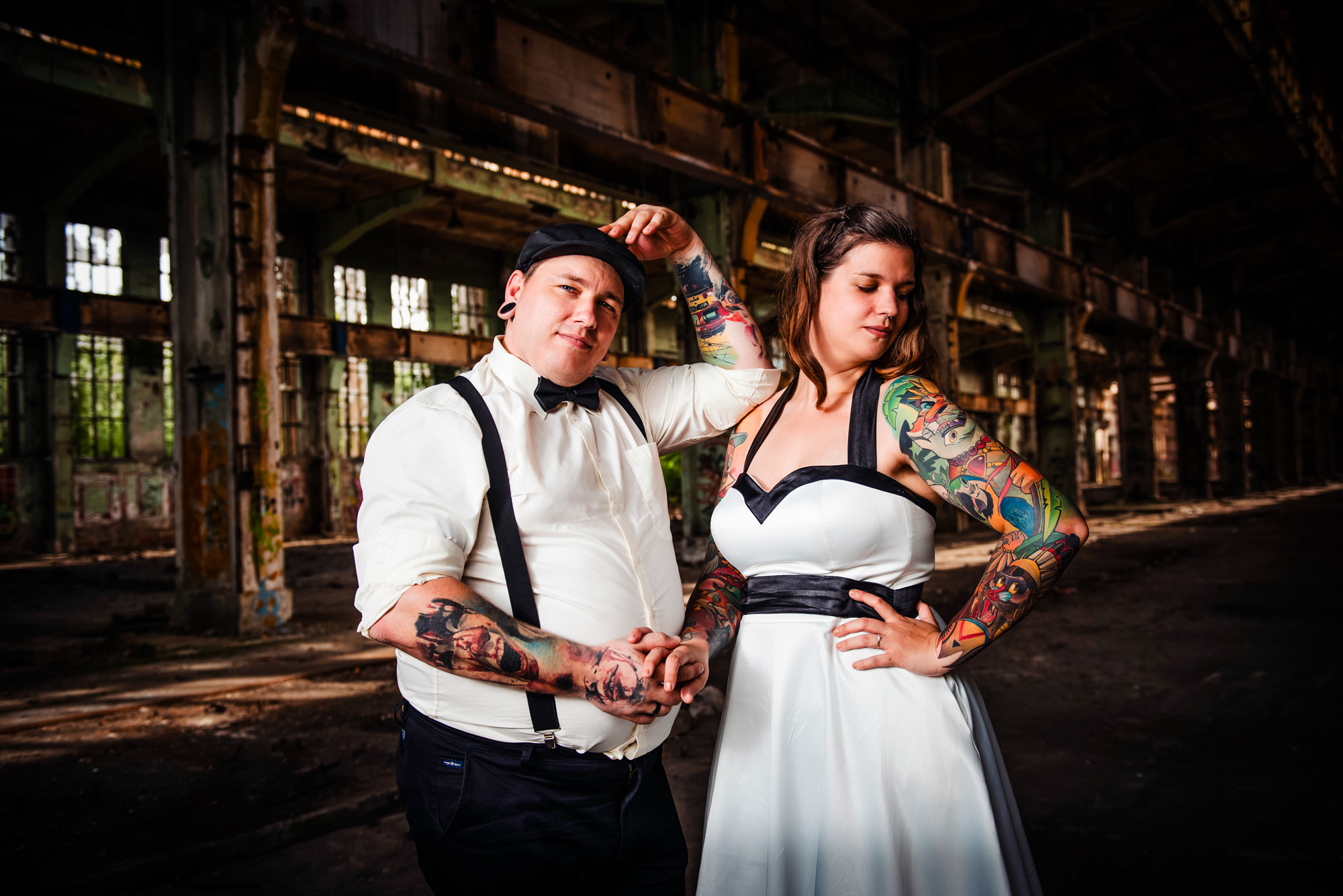 Alternative bride and groom posing confidently inside dramatic industrial wedding location in Budapest.