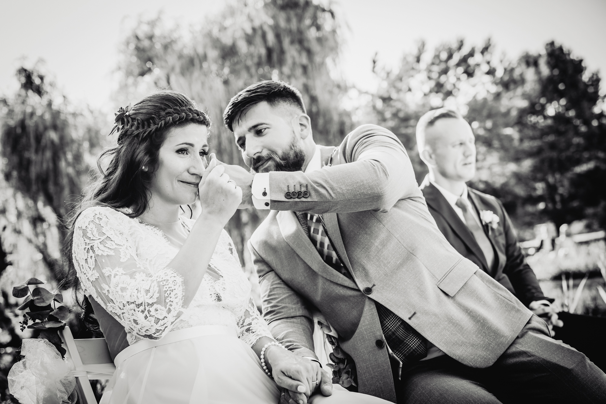 Groom gently wipes tears from the bride's face during an emotional ceremony moment.
