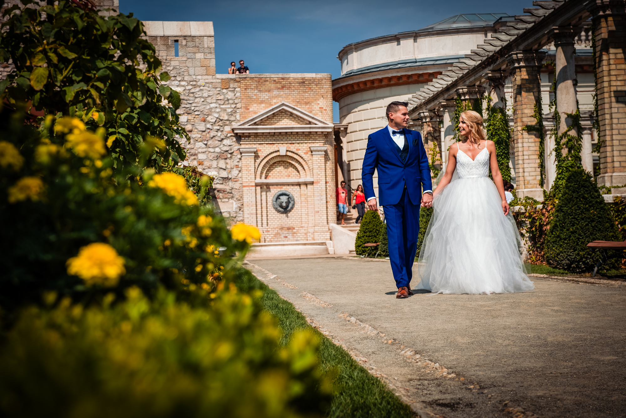 Bride and groom walking through Castle Garden Bazaar in Budapest on a sunny summer wedding day.