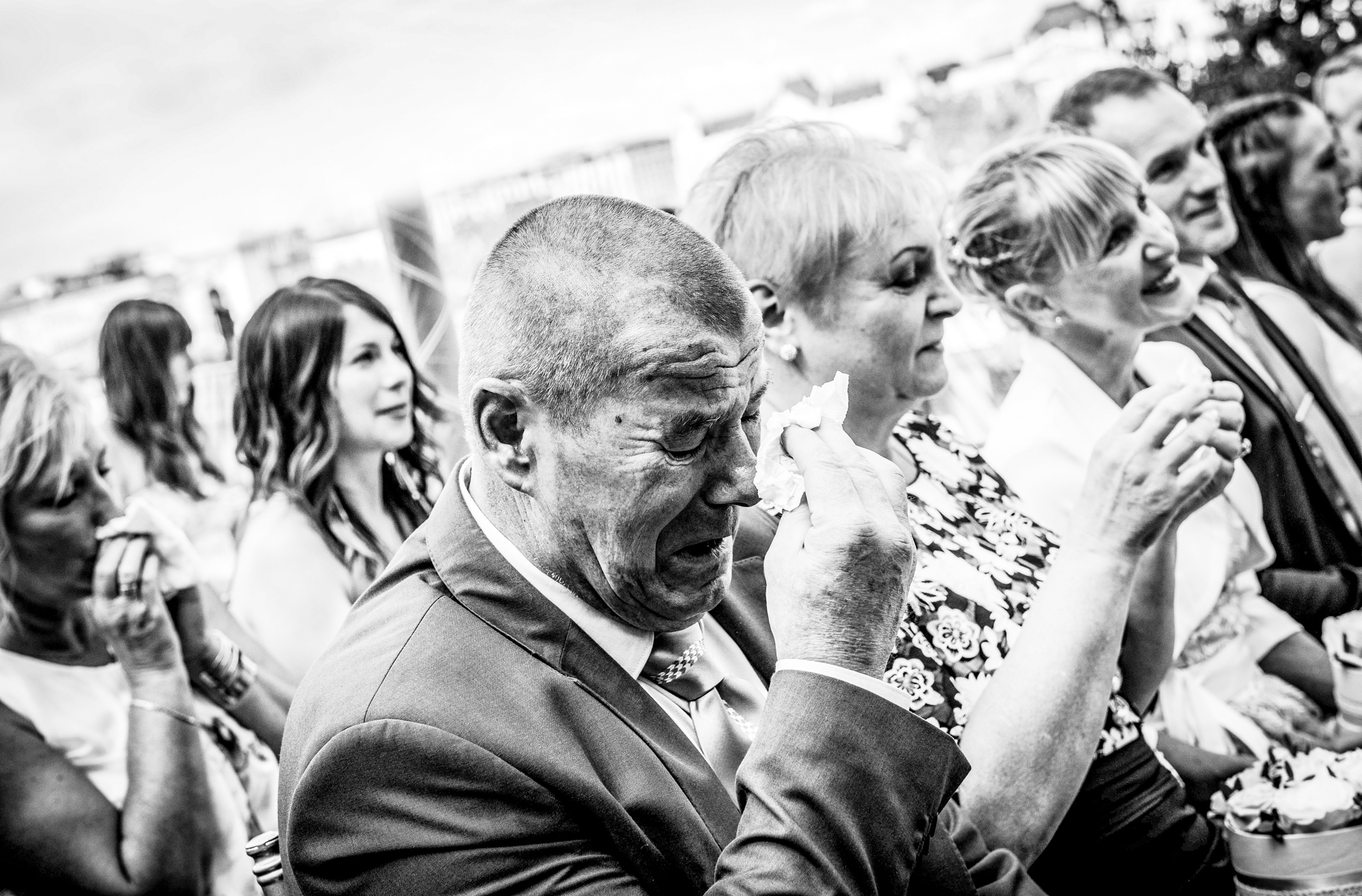 Emotional wedding guest wiping away tears during outdoor ceremony in Budapest.