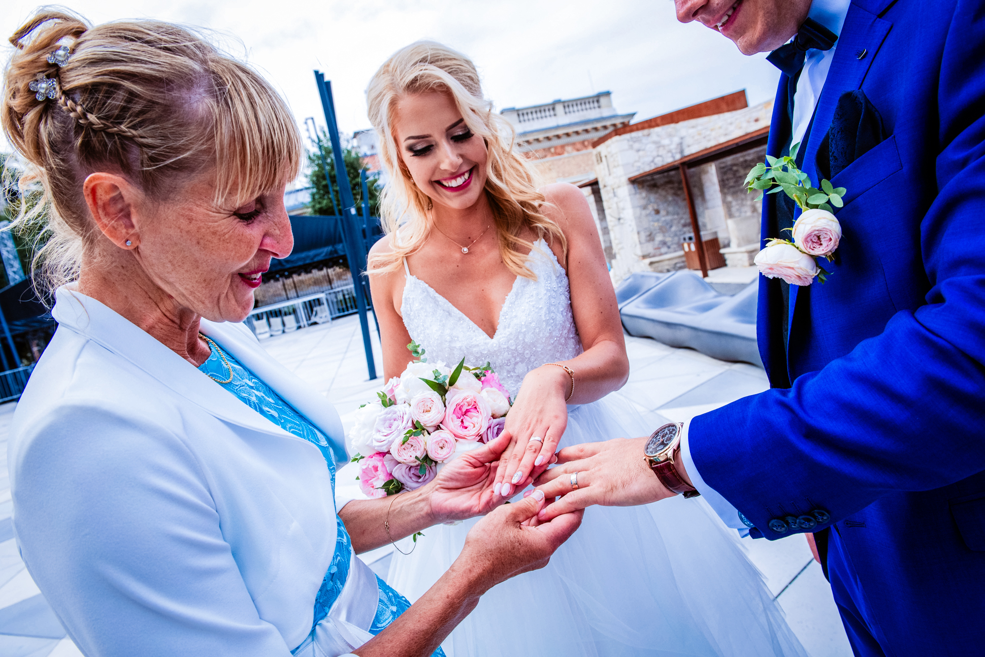Bride showing wedding ring to family member after outdoor ceremony in Budapest.