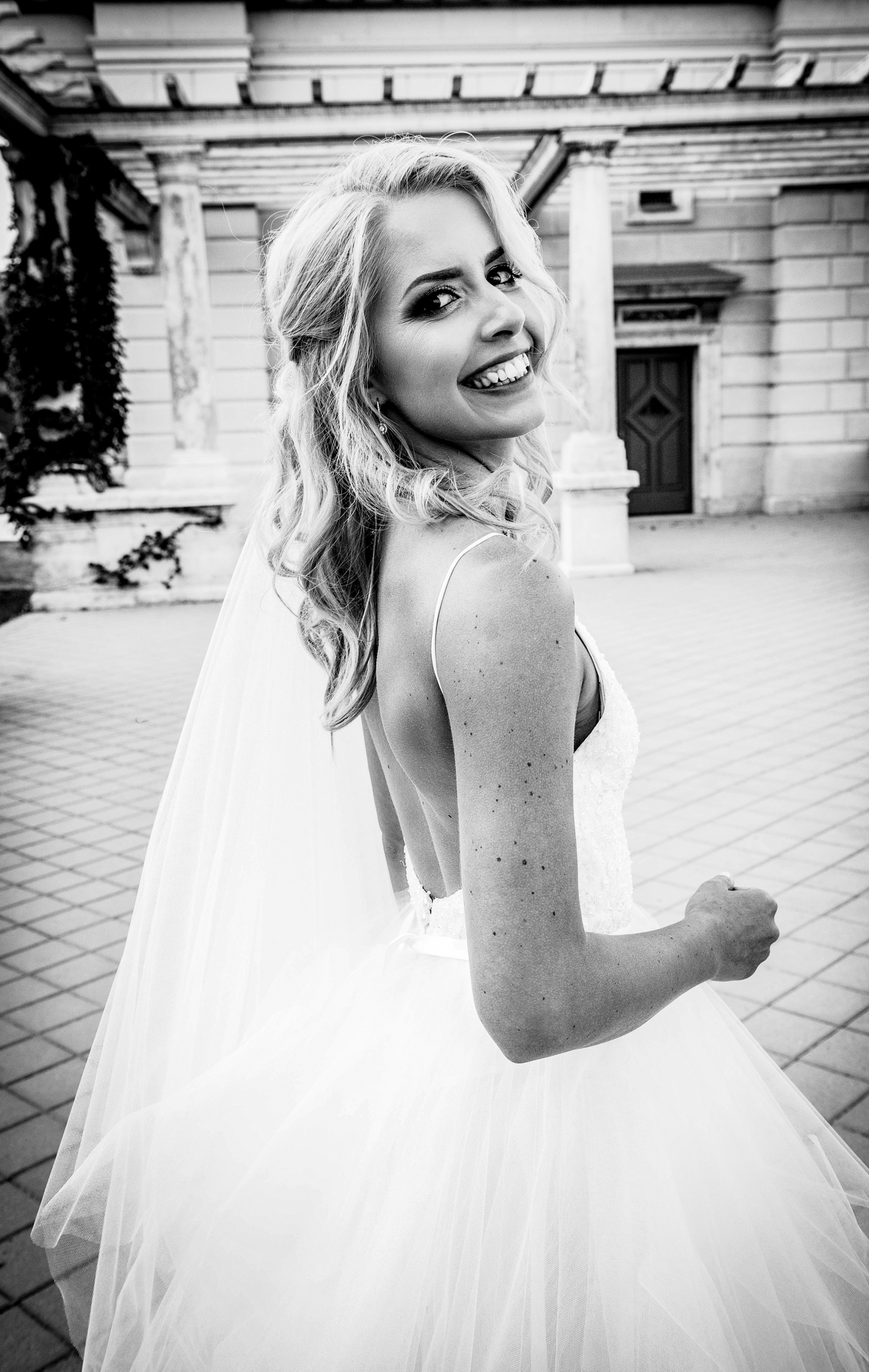 Smiling bride in flowing wedding dress and veil during bridal portraits at Castle Garden Bazaar Budapest.