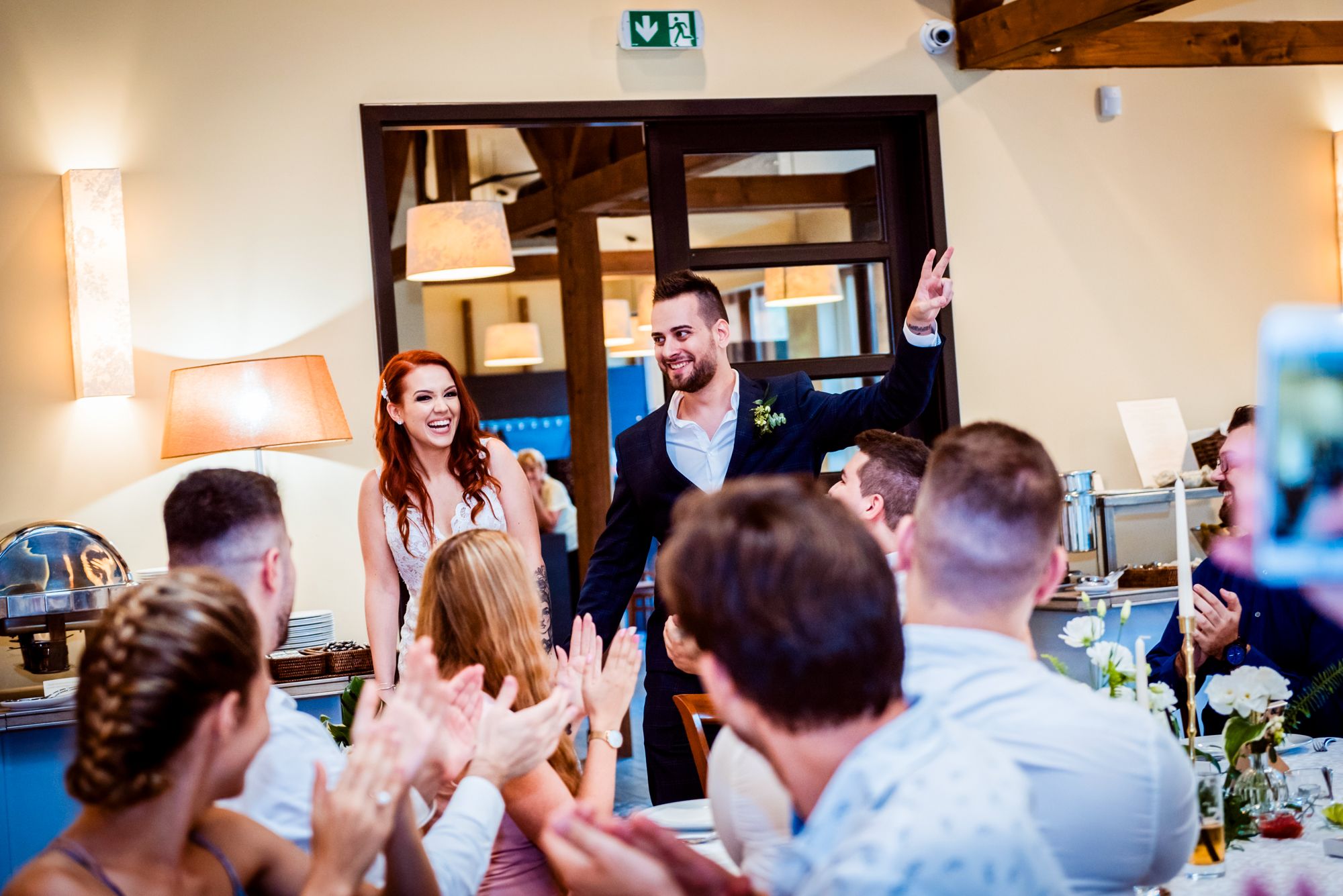 Newlyweds enter the reception to applause from family and friends gathered around tables.