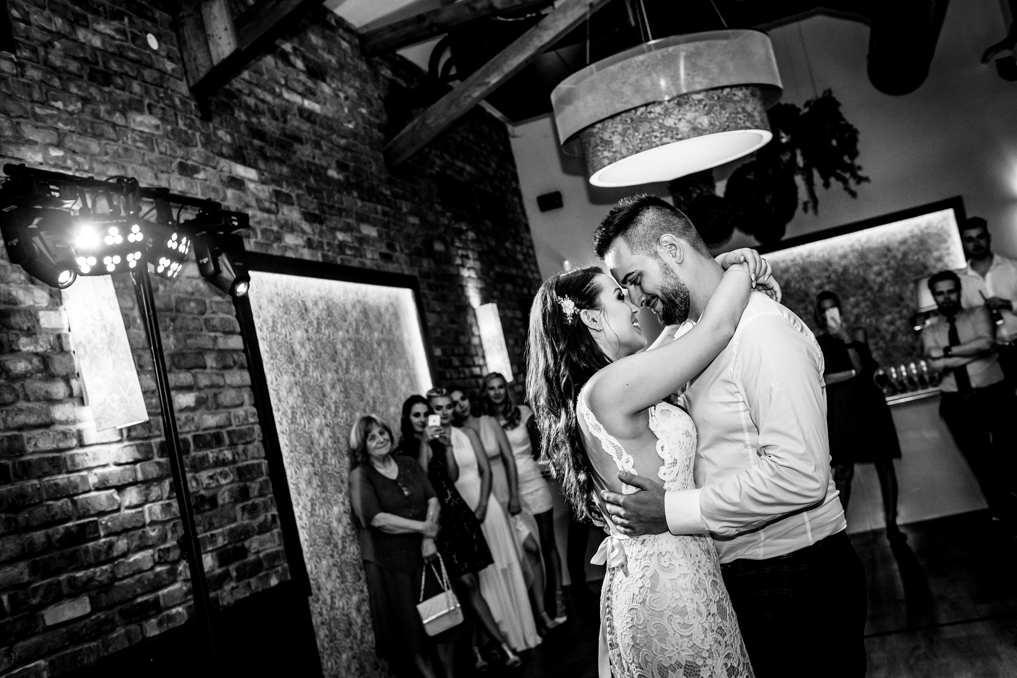 Bride and groom share their first dance while guests watch from the edge.