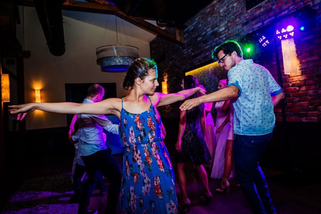 Guests dance energetically beneath purple and blue lights during the evening party.