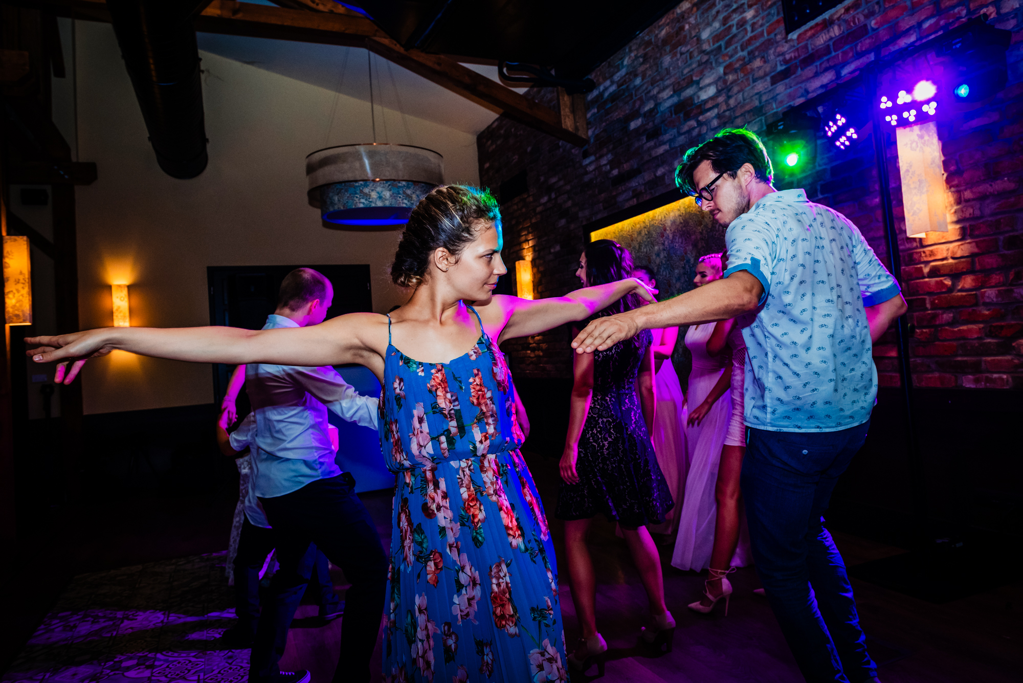 Guests dance energetically beneath purple and blue lights during the evening party.