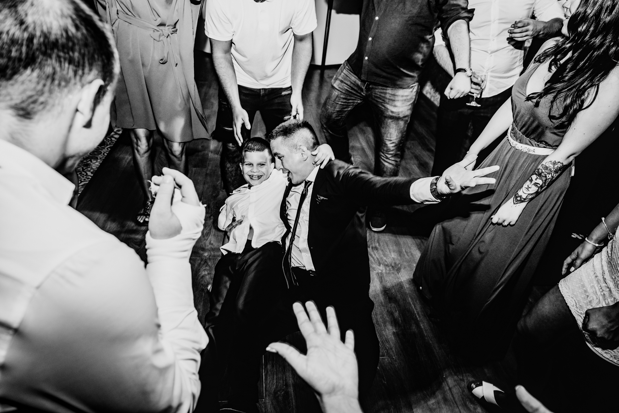 Young boy dances confidently in the centre of a circle of cheering guests.