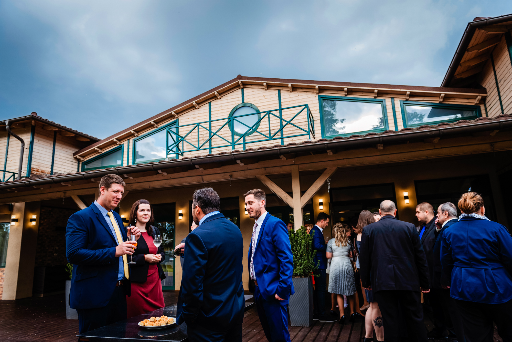 Guests gathered outside Duna Garden Hotel before outdoor wedding ceremony under cloudy skies.