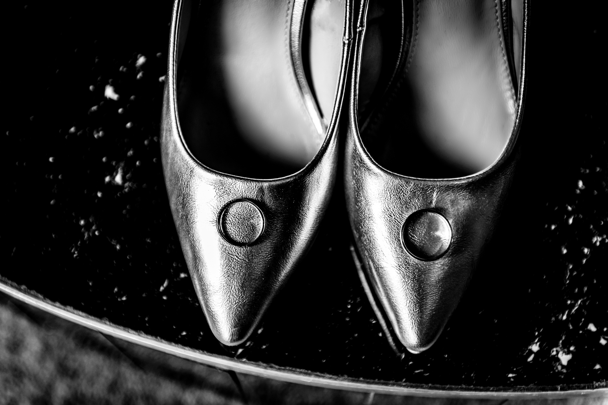 Black pointed bridal shoes photographed in dramatic light before wedding ceremony in Budapest.