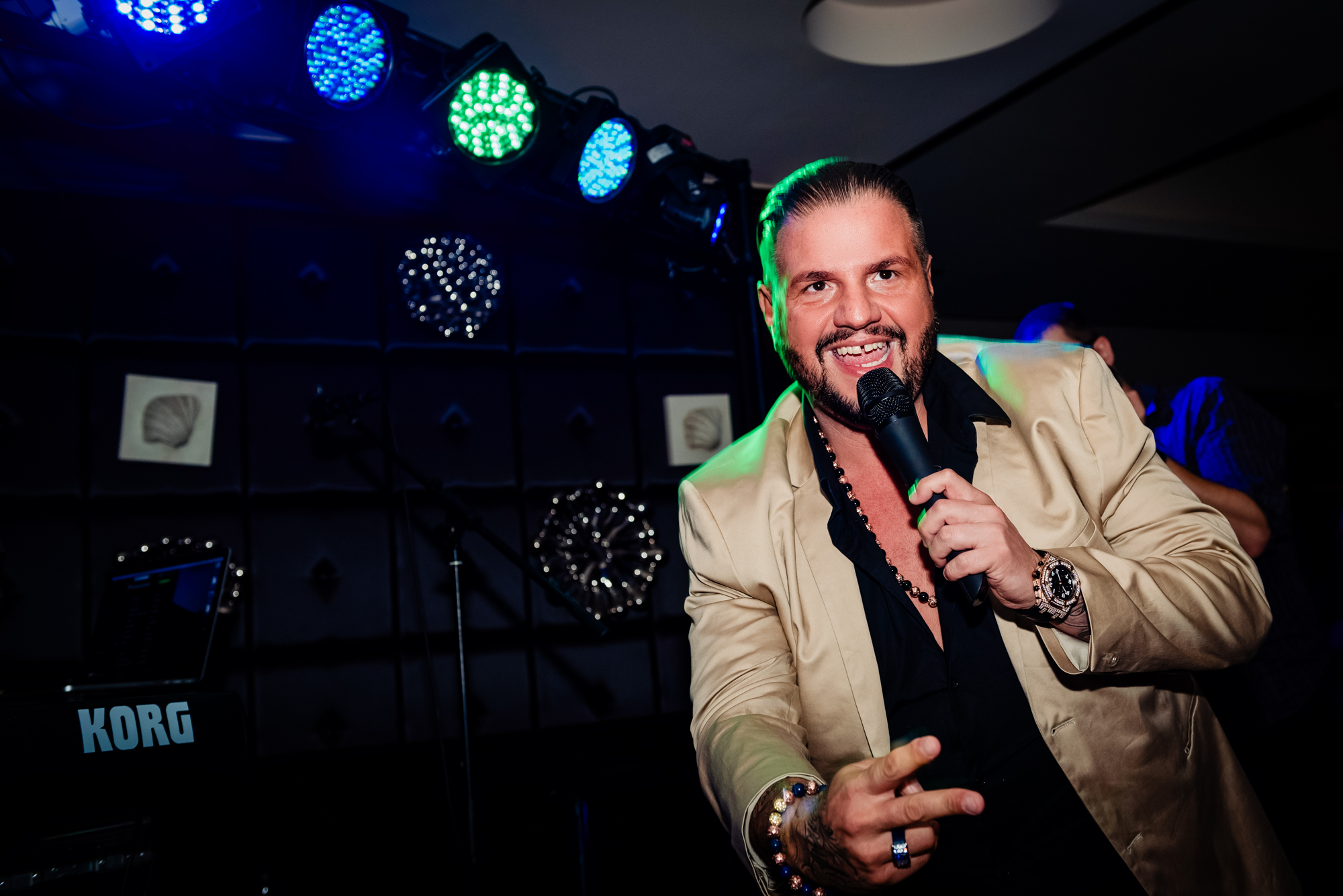 Wedding singer performing at Duna Garden Hotel reception with colourful stage lights and microphone.