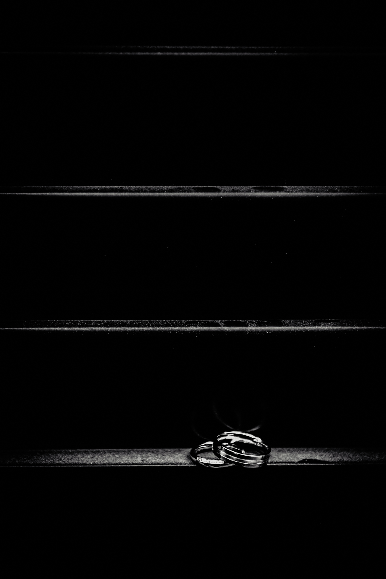Wedding rings placed on dark wooden staircase steps.