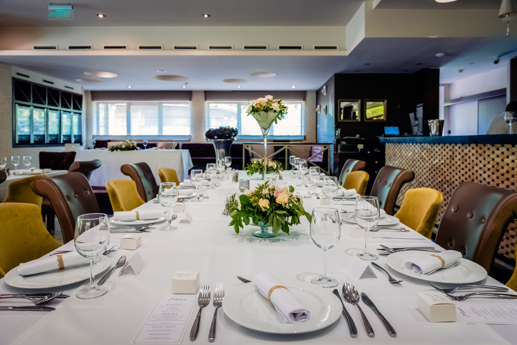 Long wedding reception table with floral arrangements and place settings at Budapest wedding venue.