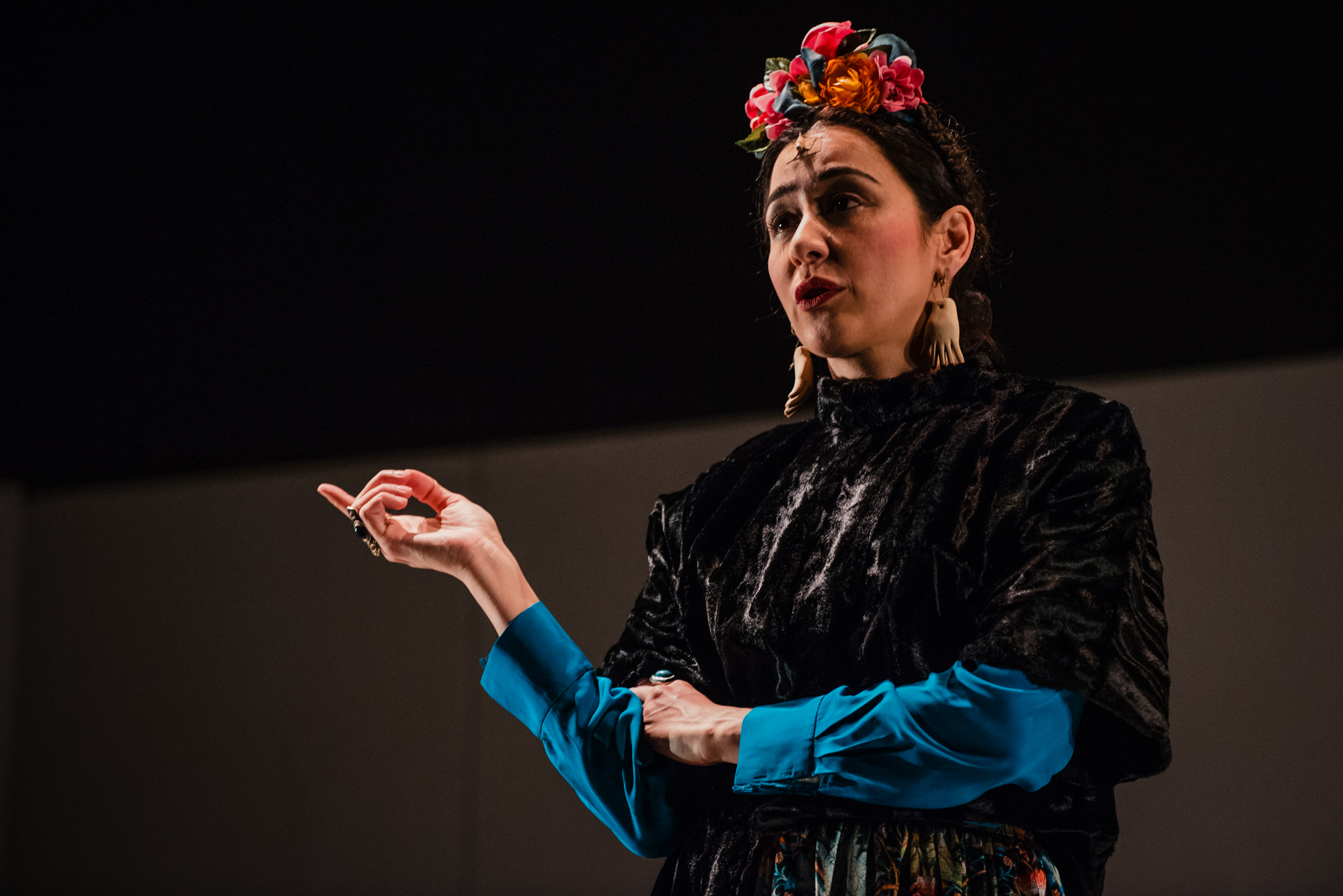 Performer dressed as Frida Kahlo gestures dramatically during contemporary musical theatre performance.