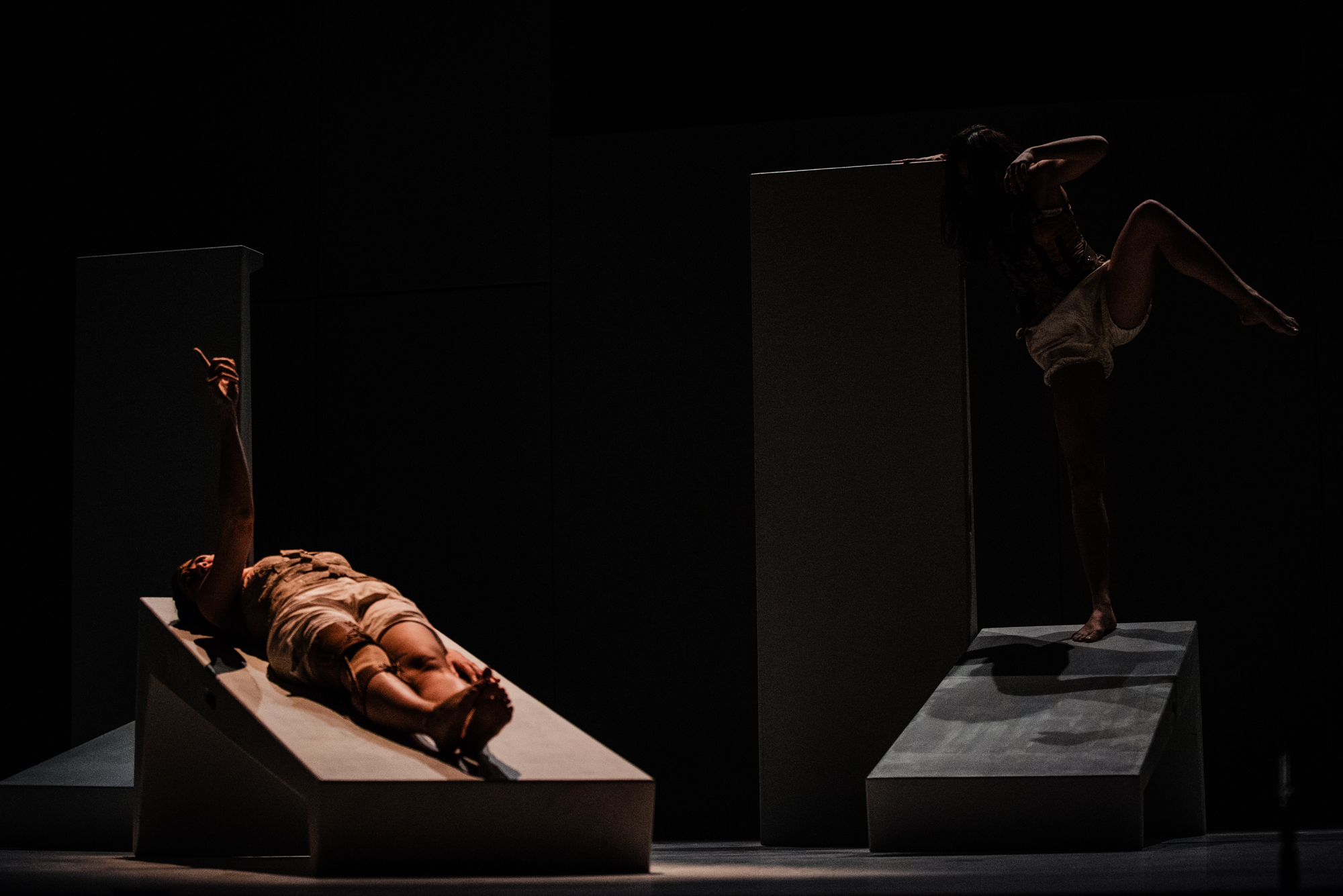 Two performers move across minimalist stage set during contemporary Frida Kahlo theatre production.