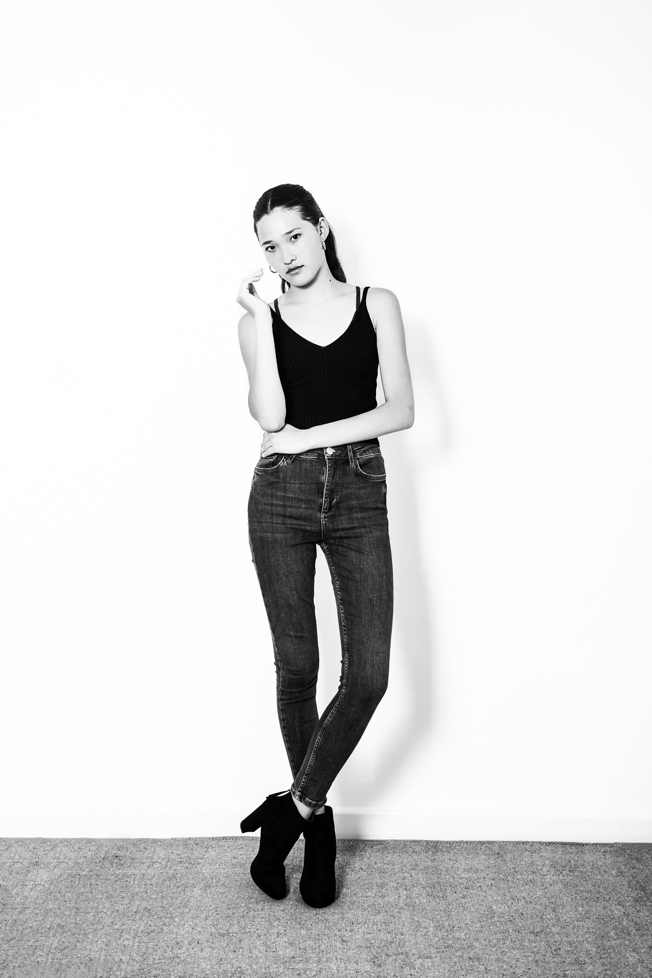 Black and white full-length portrait of young model standing confidently during indoor portfolio session.