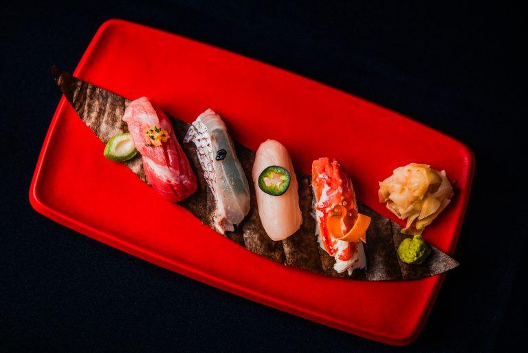 Assorted nigiri sushi presented on a red platter with wasabi and pickled ginger at Nobu Budapest restaurant.