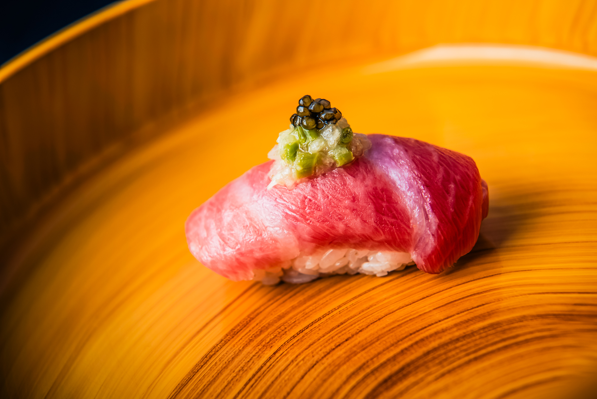 Wagyu nigiri topped with caviar and scallion relish on a wooden serving board at Nobu Budapest.