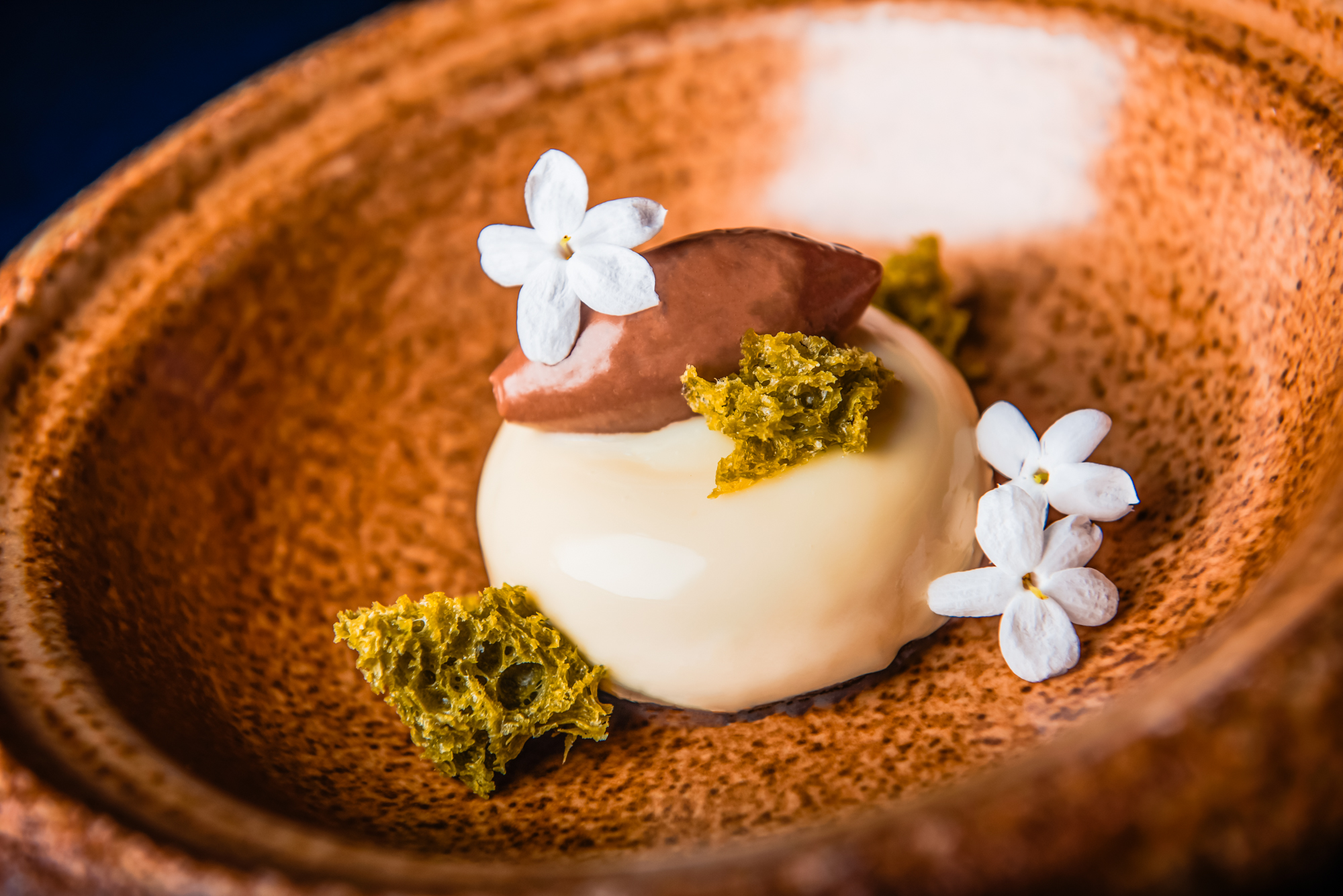 White chocolate mousse dessert topped with edible flowers and crisp green garnish.