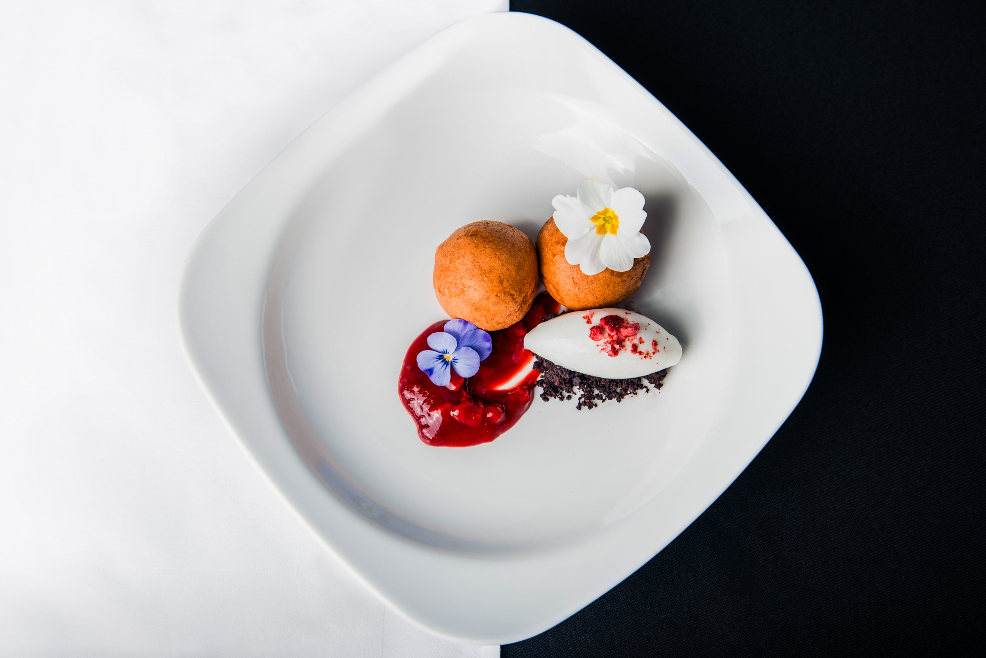 Elegant plated dessert featuring chocolate truffles, berry coulis, and floral garnishes at Nobu Budapest.
