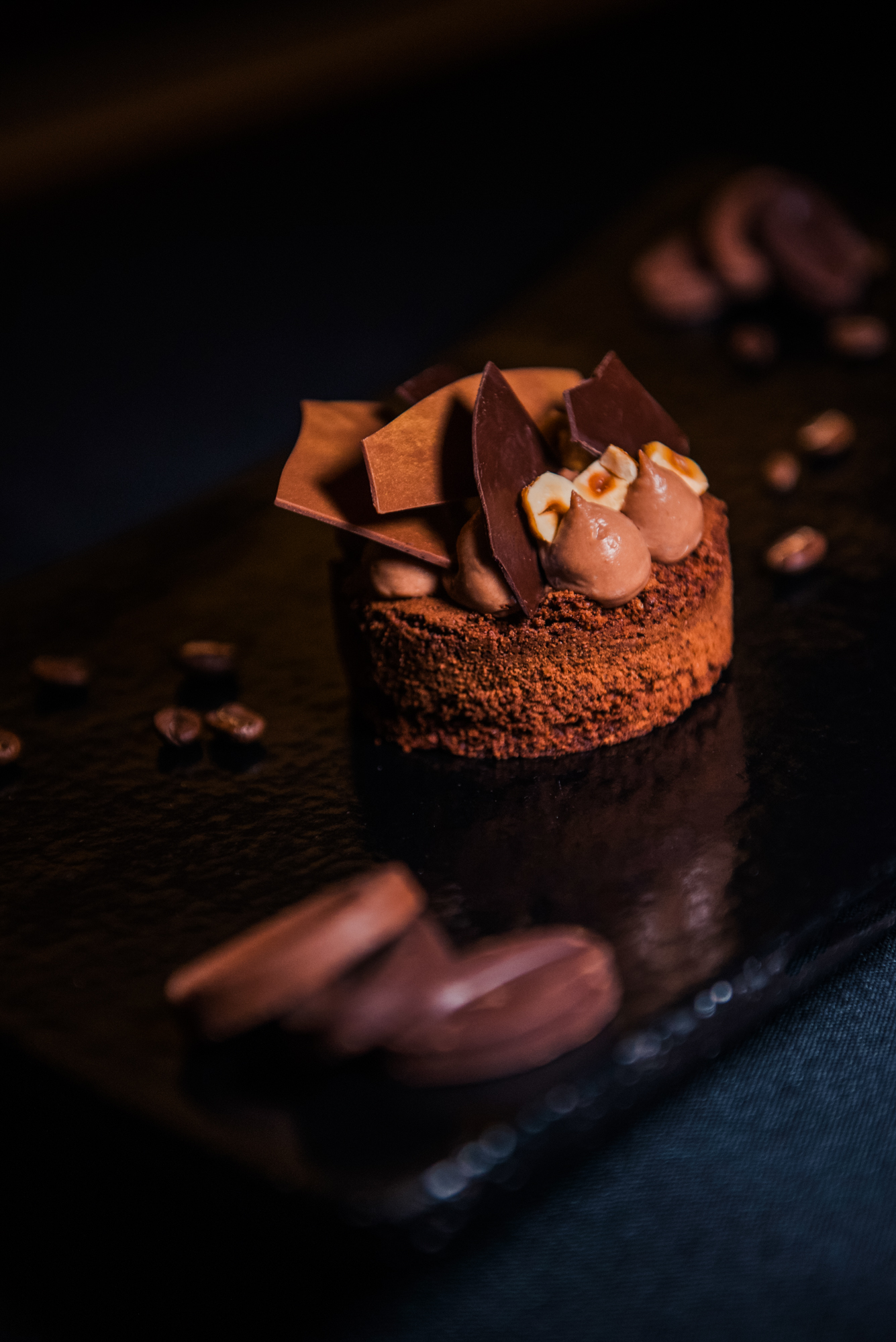 Close-up of chocolate tart with chocolate cream, hazelnuts, and decorative chocolate pieces at Nobu Budapest.