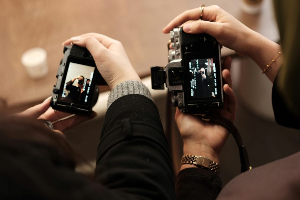 Two photographers reviewing images on camera screens during a wedding, showing different angles.