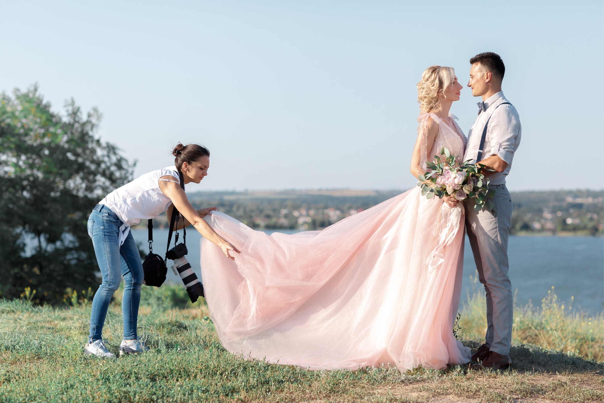 Photographer adjusting a bride’s dress during a portrait session to prepare for a styled shot.