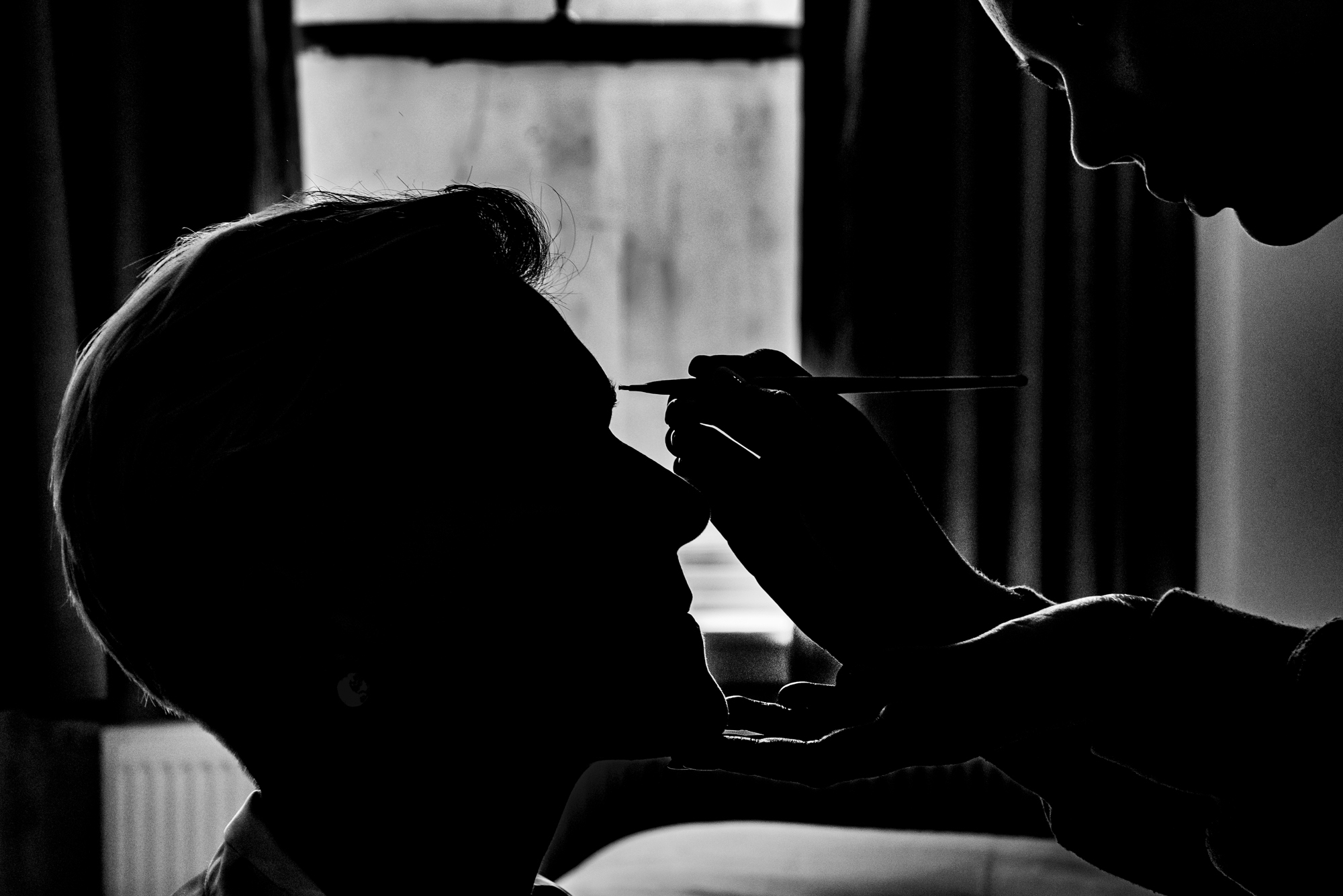 Silhouette of makeup artist applying eyeliner in soft morning light