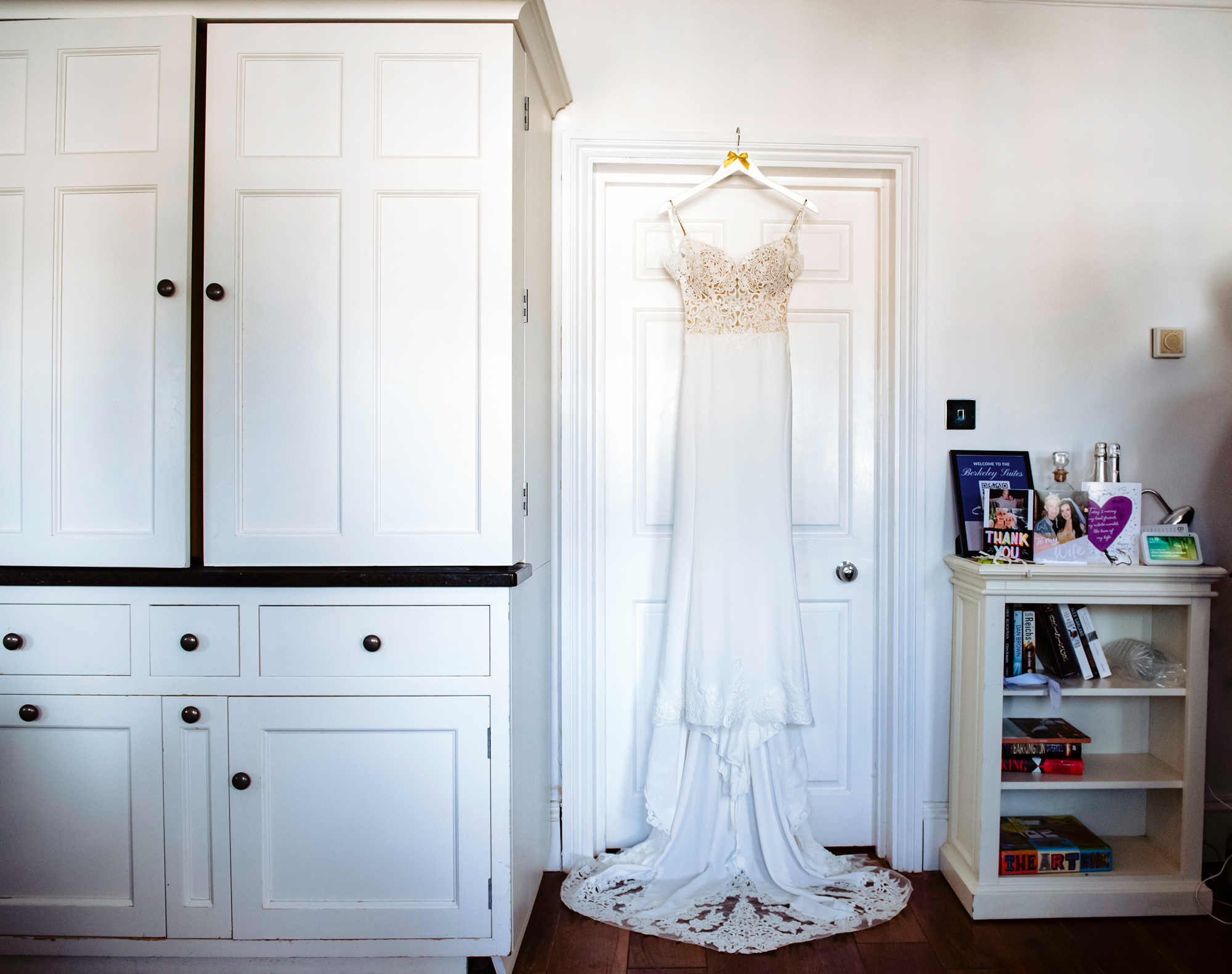 Lace-detailed wedding dress hanging on white door